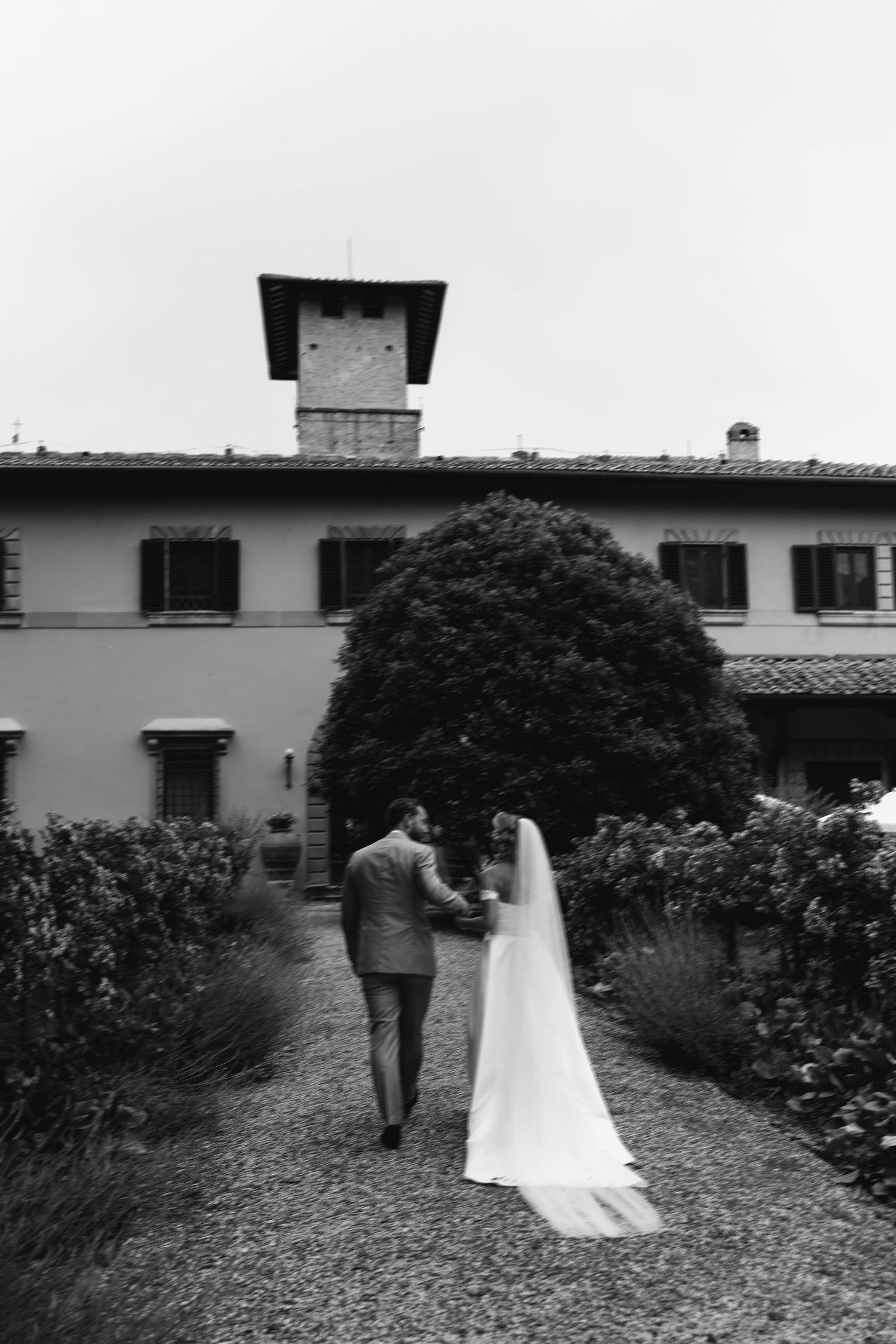 A cinematic black and white wedding sequence showing a couple walking together through a garden path.