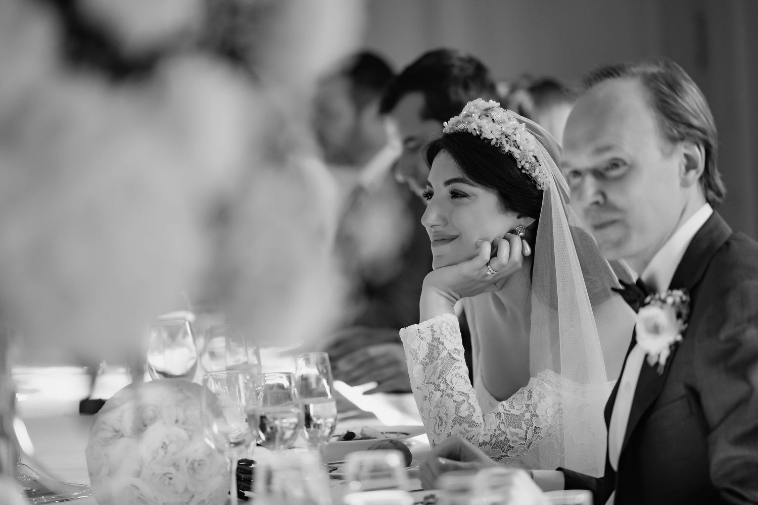 Black and white wedding reception photo showing guests seated at table with candlelight and formal table settings.