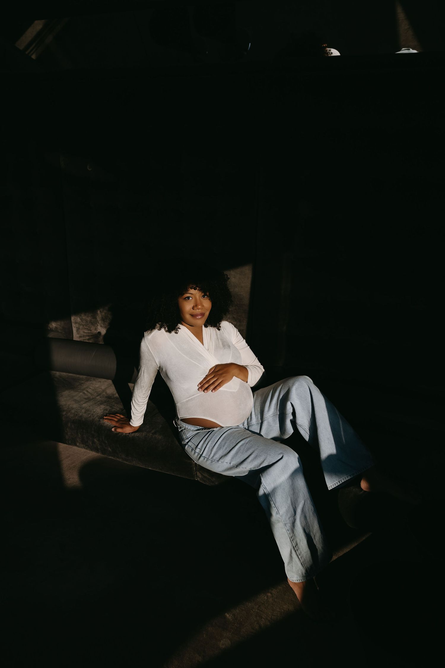Maternity portrait in white crop top and casual pants with natural lighting.