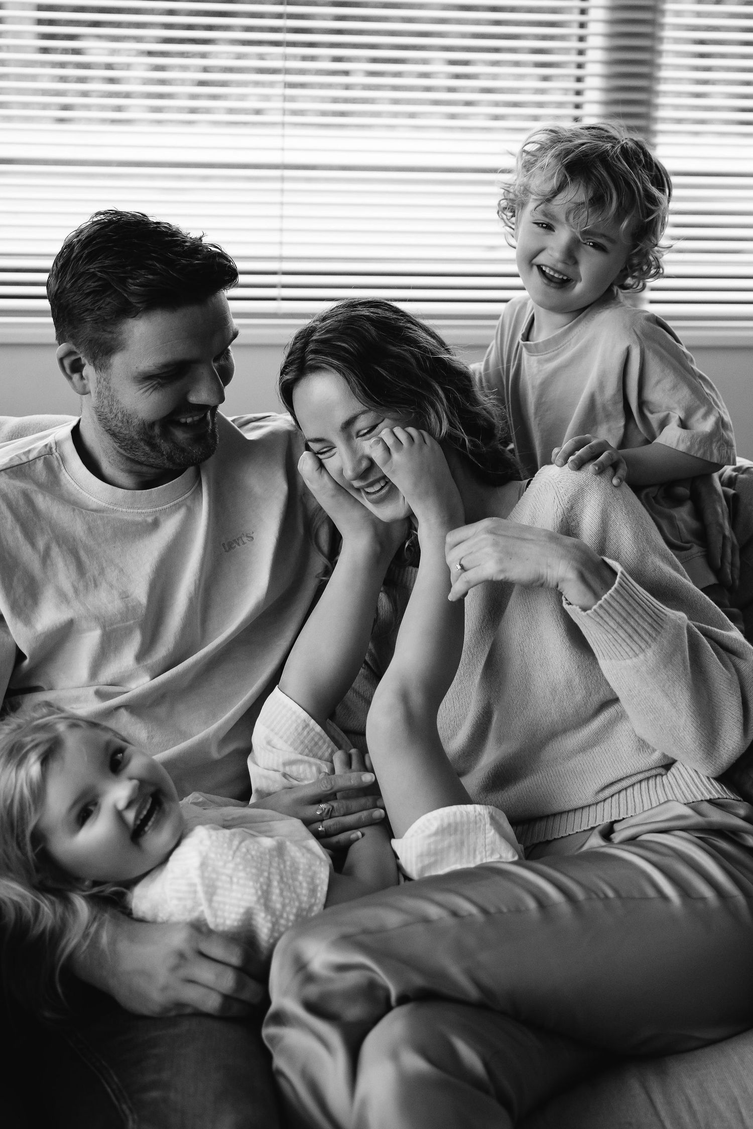 Candid black and white photography of family members relaxing together on a couch.