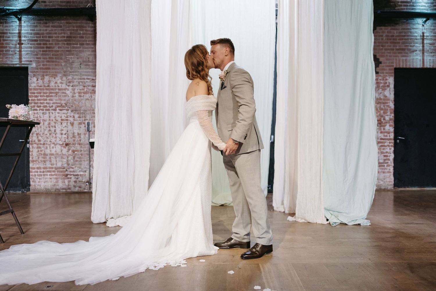 A series of intimate wedding moments against white drapes and industrial brick walls.