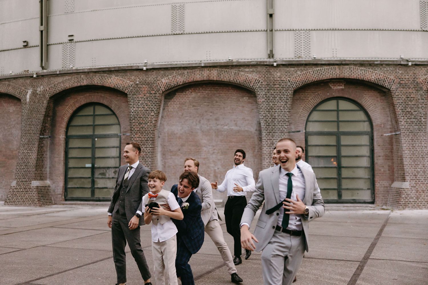 Group running playfully outside a building with arched green doors.
