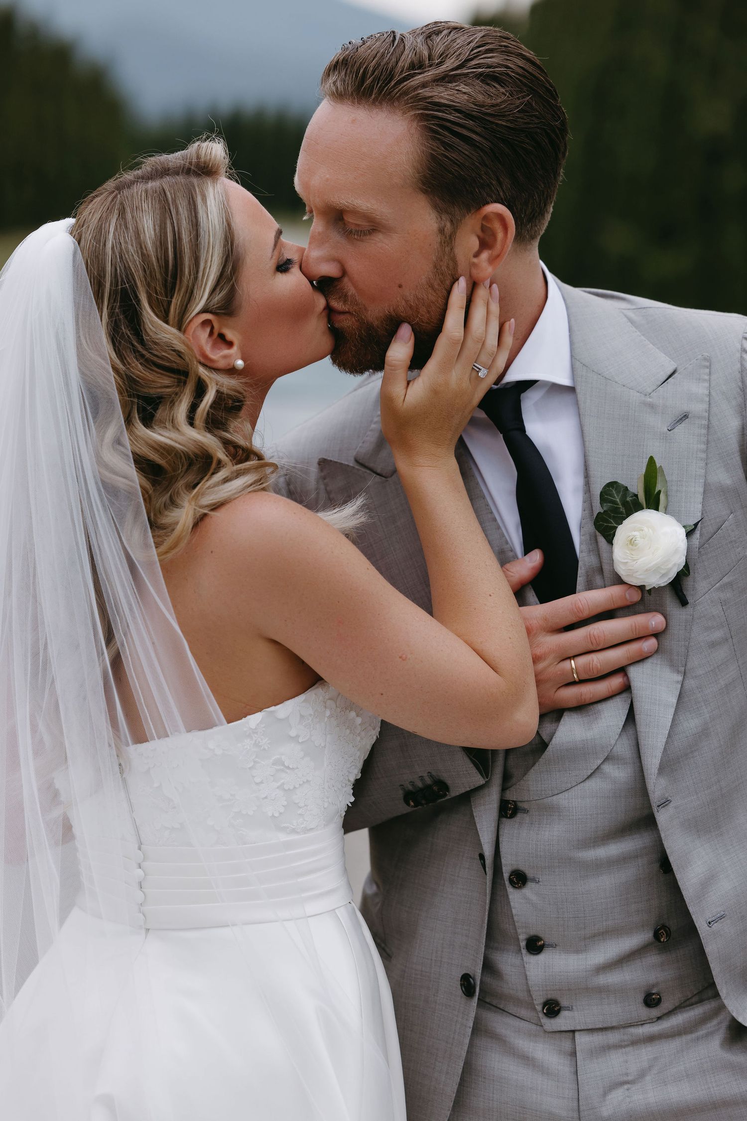 A romantic wedding moment captured between newlyweds wearing traditional white dress and grey suit.