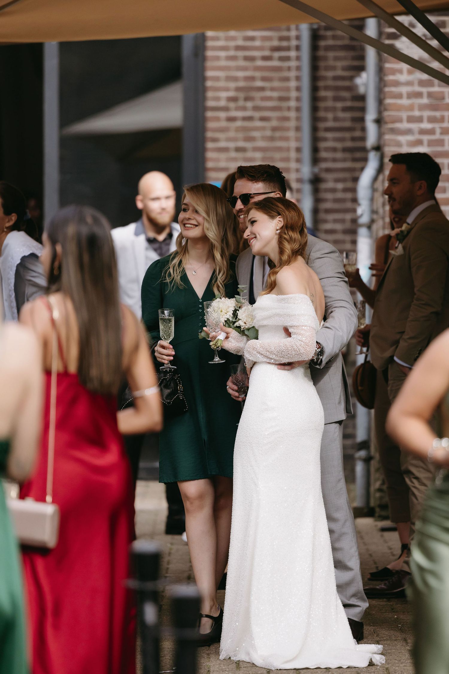 Wedding guests mingle during an outdoor cocktail reception at a brick venue.