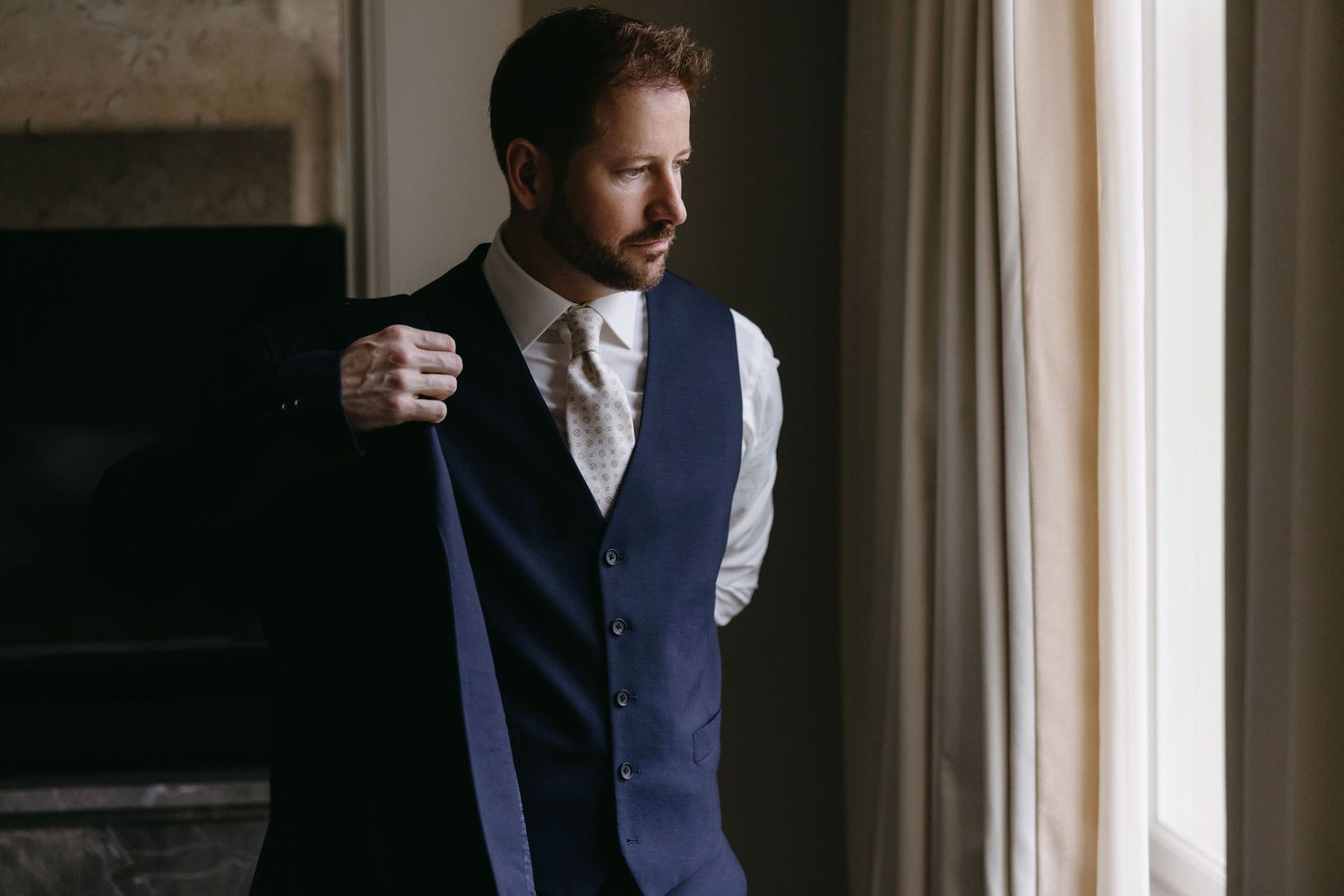 Dramatic window light illuminating figures in formal attire.