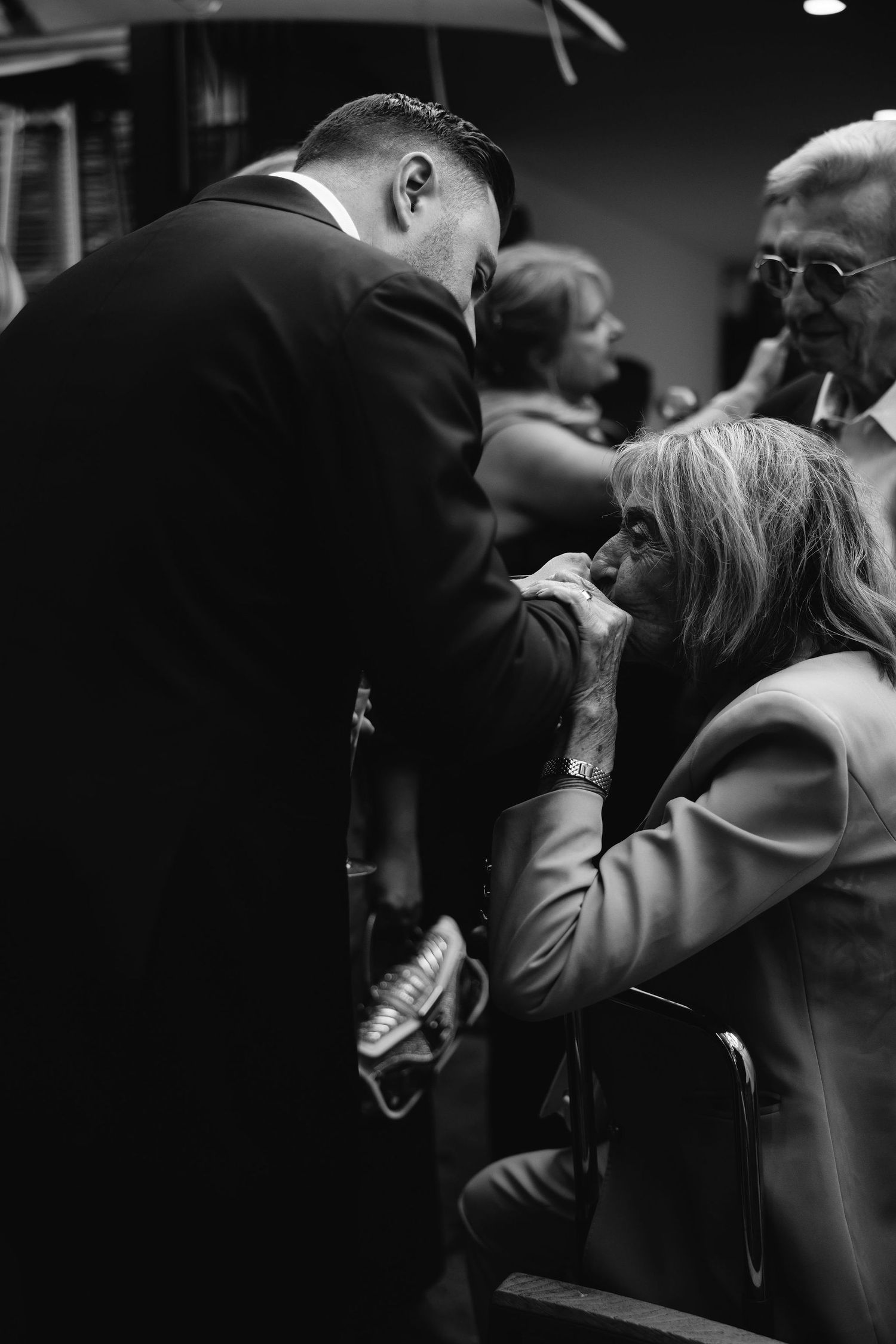 Black and white candid moment between wedding guests during reception.