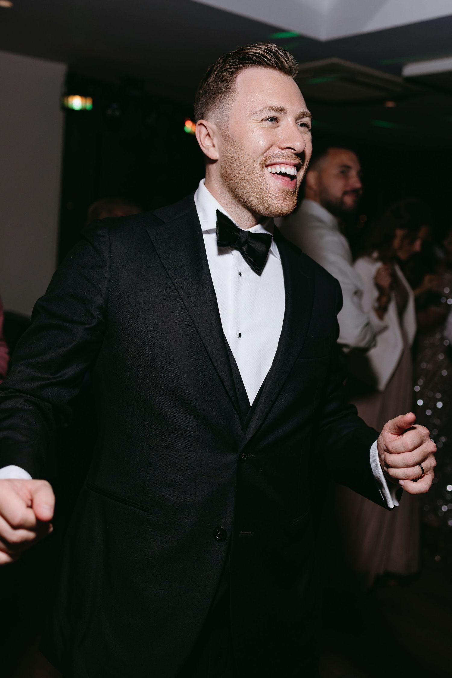 Formal event guest in black tuxedo and bow tie enjoys celebration.