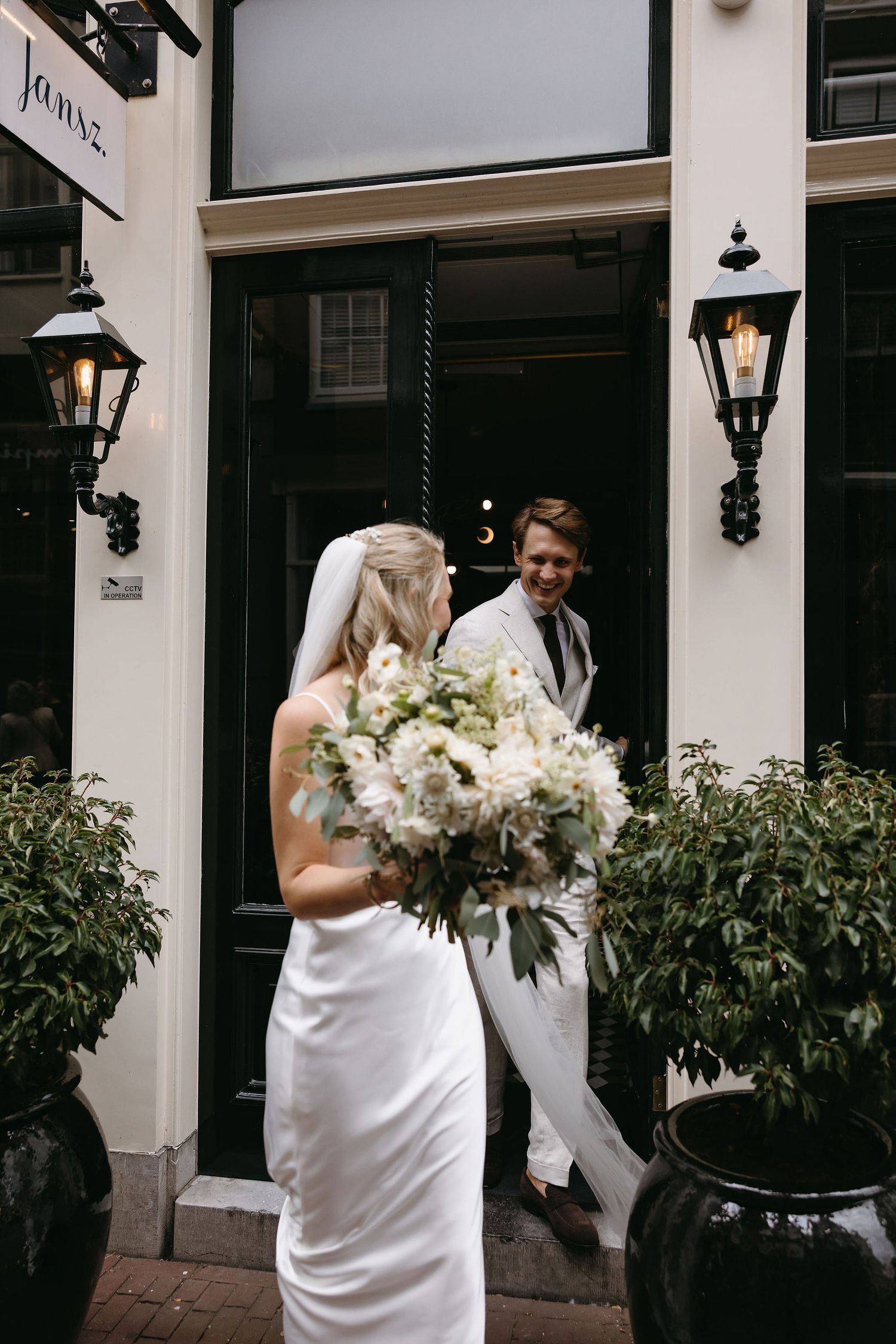 Wedding scene outside historic building with floral arrangements and formal attire.