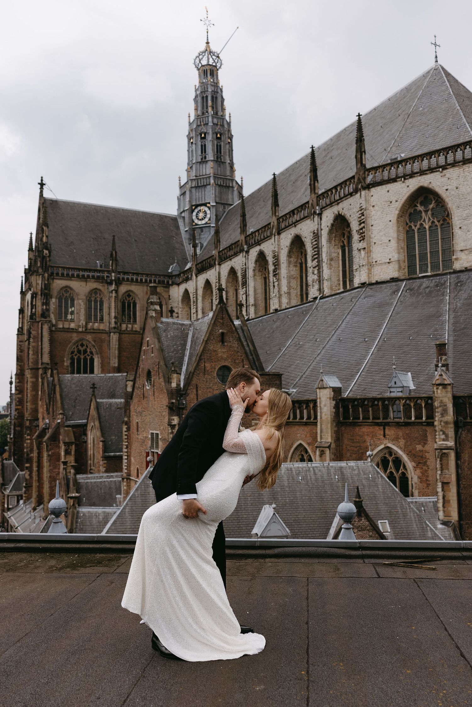 A romantic dip pose in front of a grand Gothic cathedral with dramatic architecture.