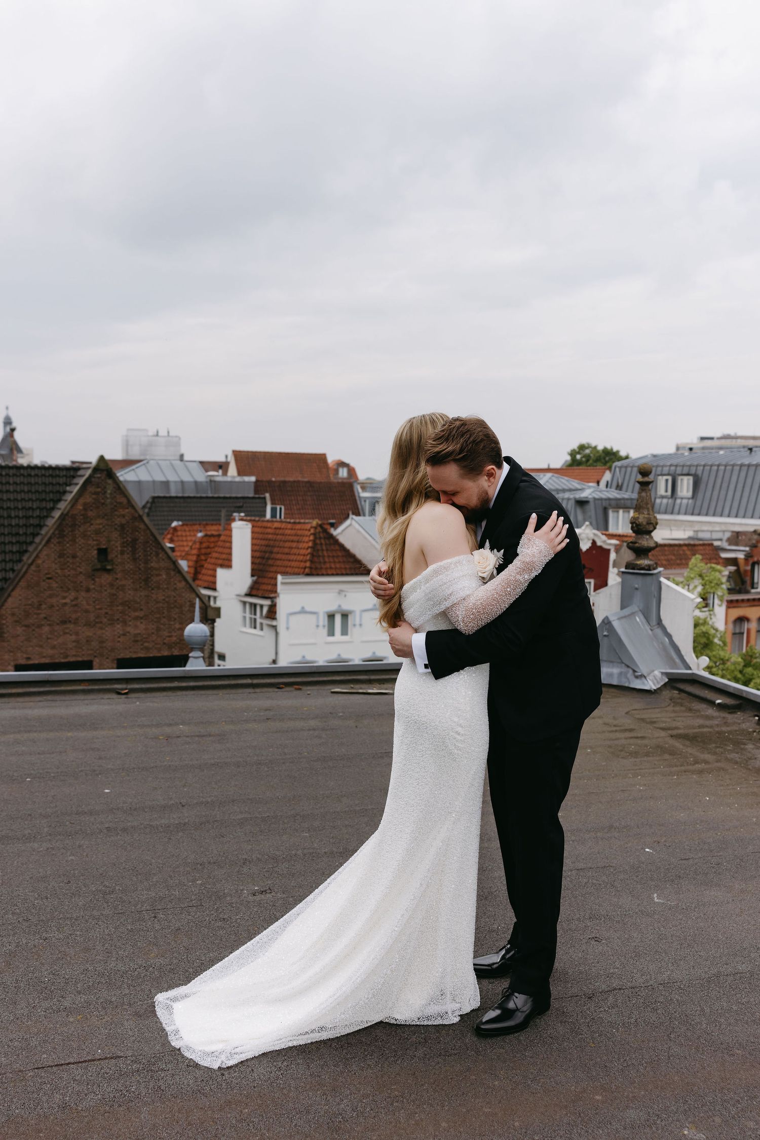 Romantic rooftop wedding moment with city buildings in background.