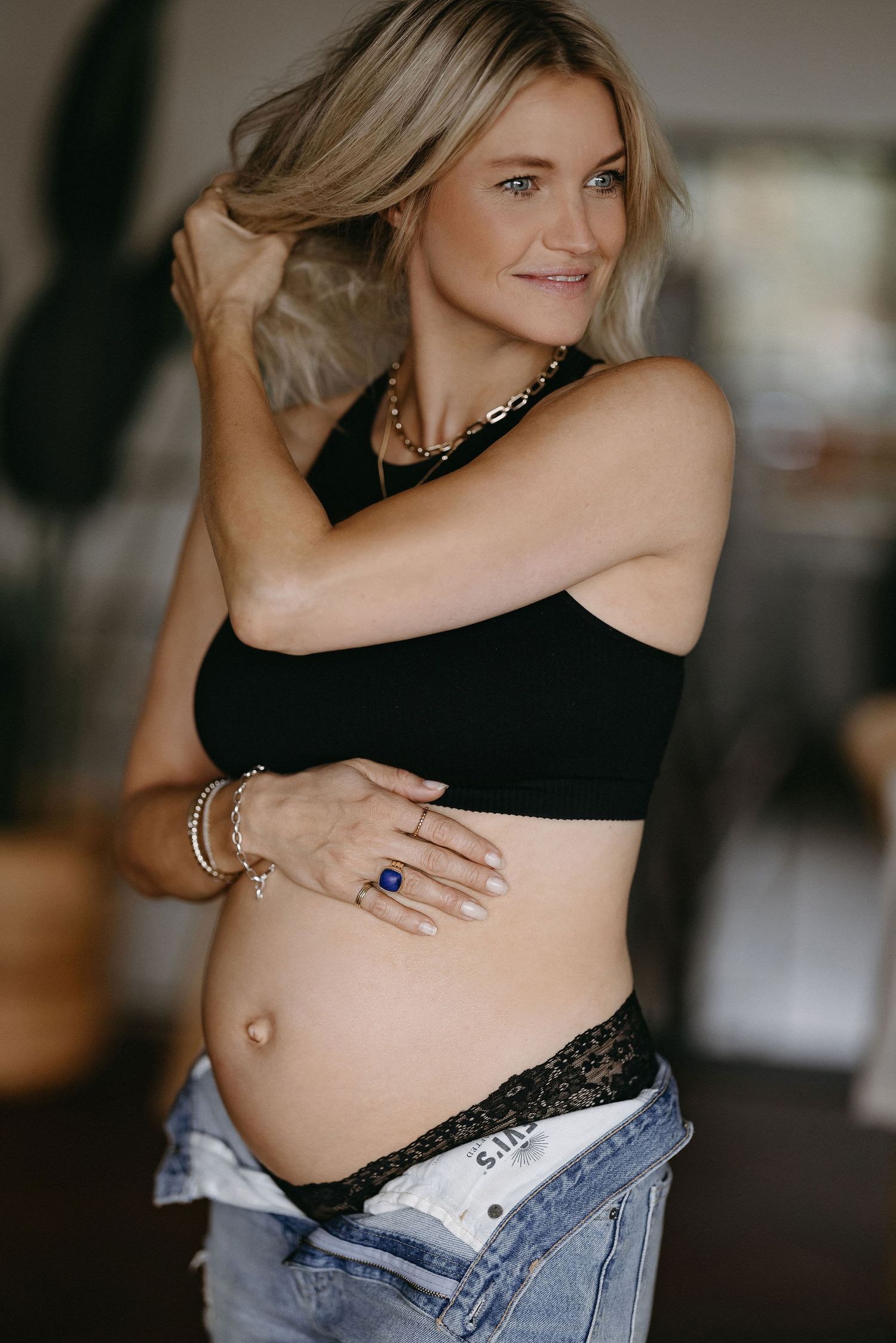 Maternity photo featuring a woman in black crop top and jeans showing her growing baby bump.