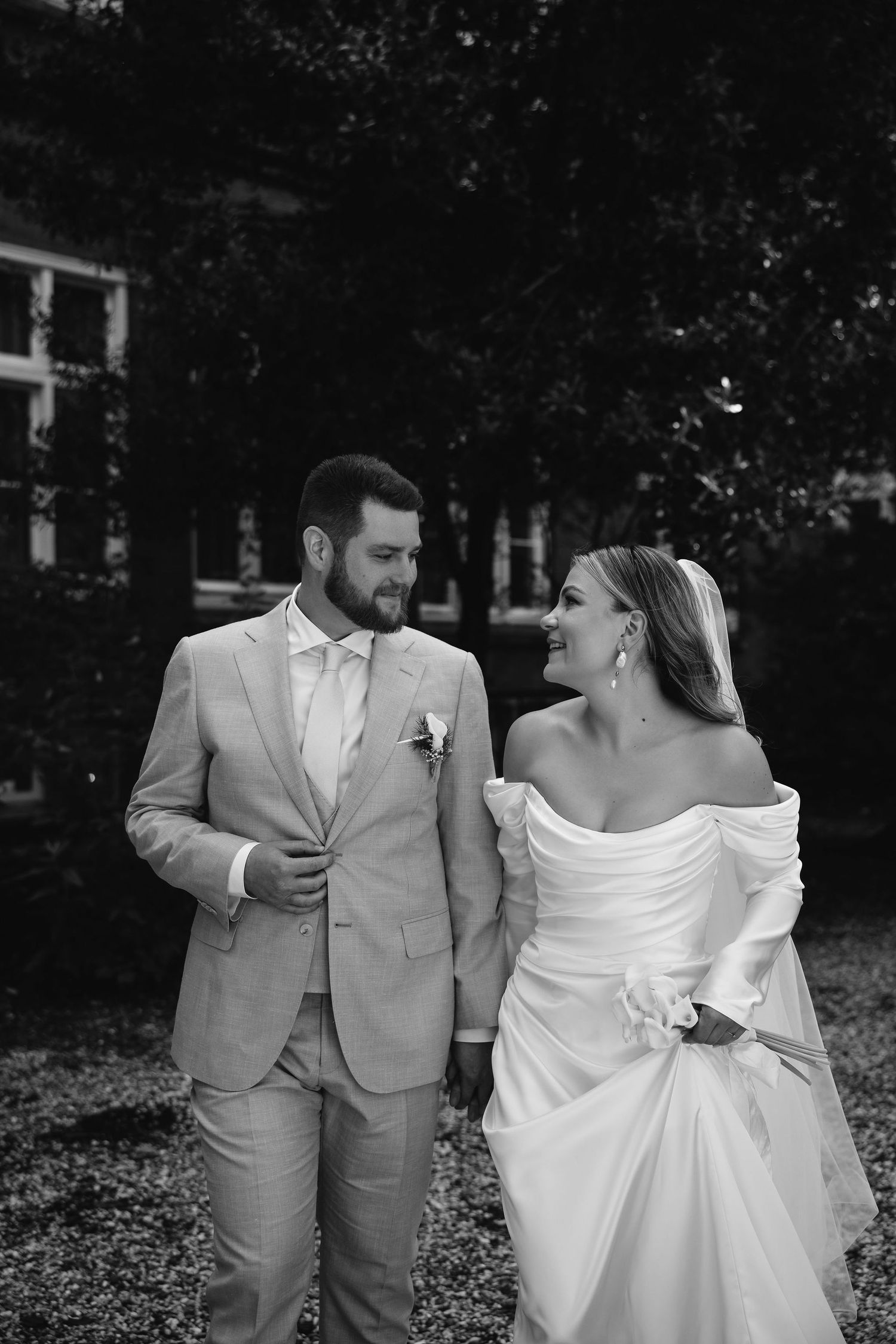 Wedding couple shares a candid moment outdoors in formal attire.