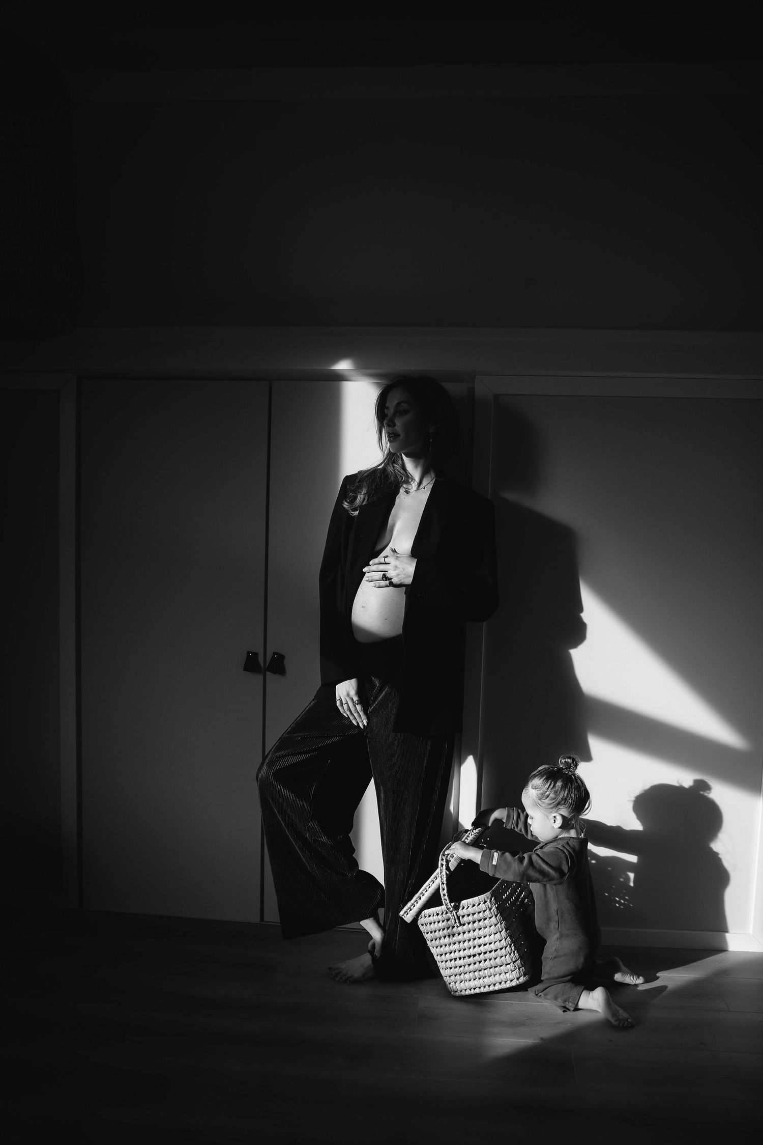 Dramatic black and white maternity photo with child playing nearby.