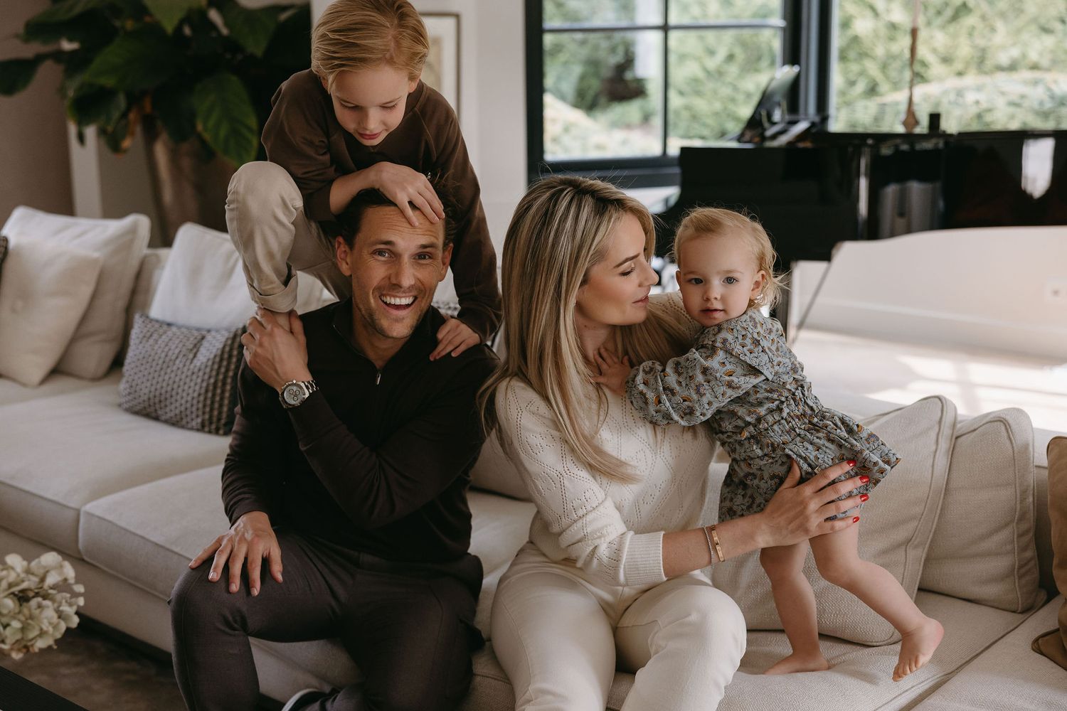 Family enjoying relaxed moments together on white couch in bright living room.
