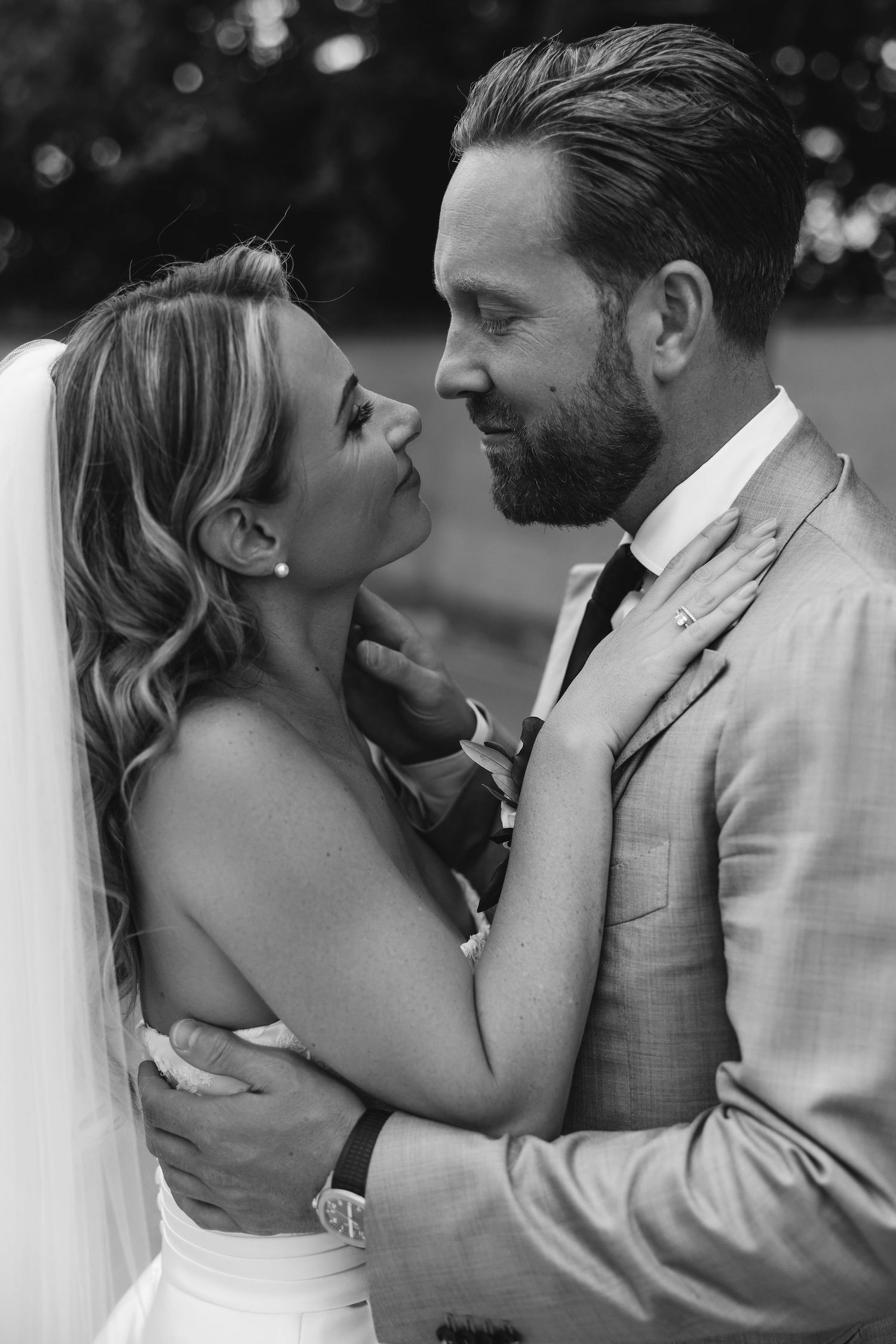 An intimate black and white moment shared between a couple in wedding attire.