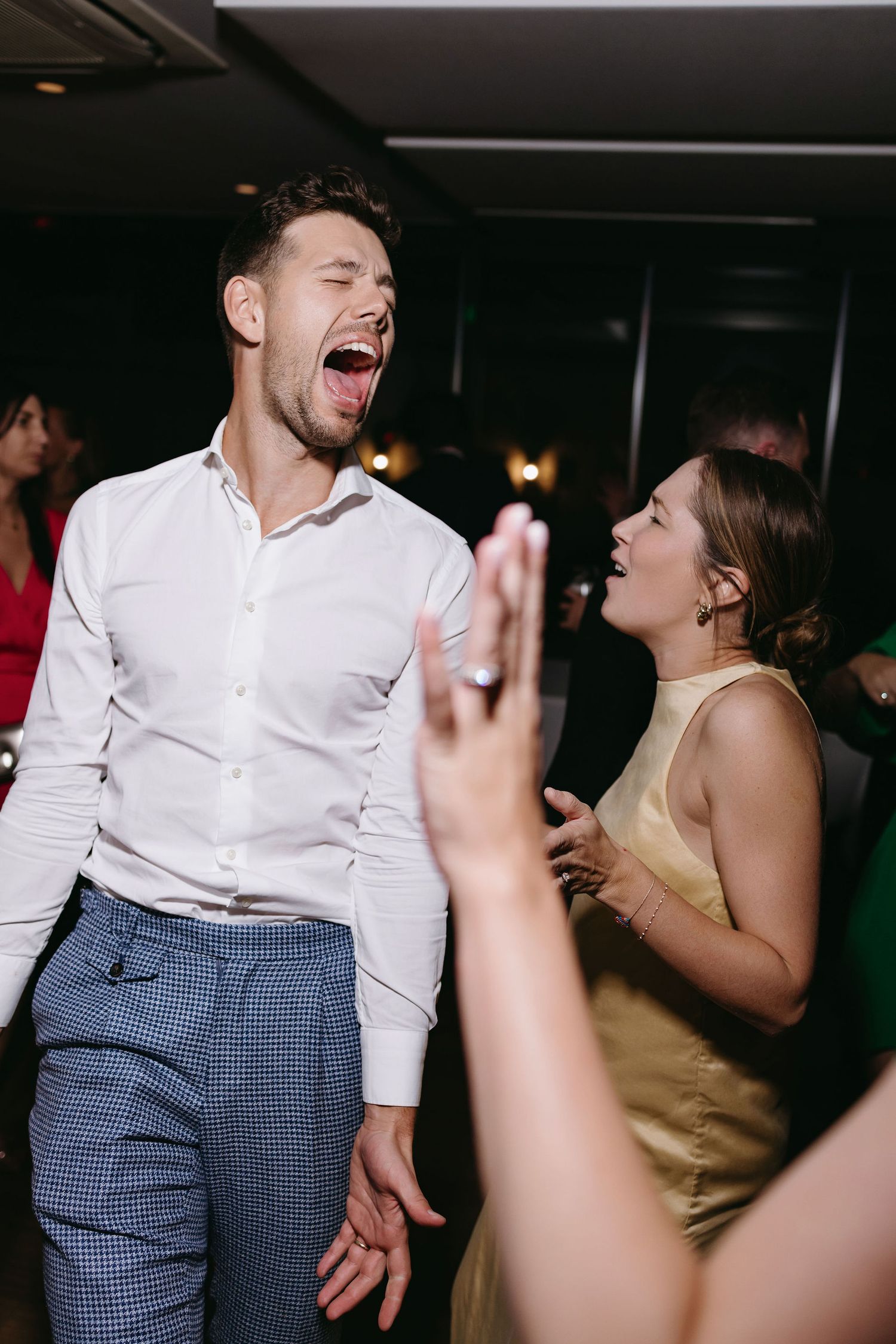 Enthusiastic wedding guests dancing and celebrating on a dark dance floor.