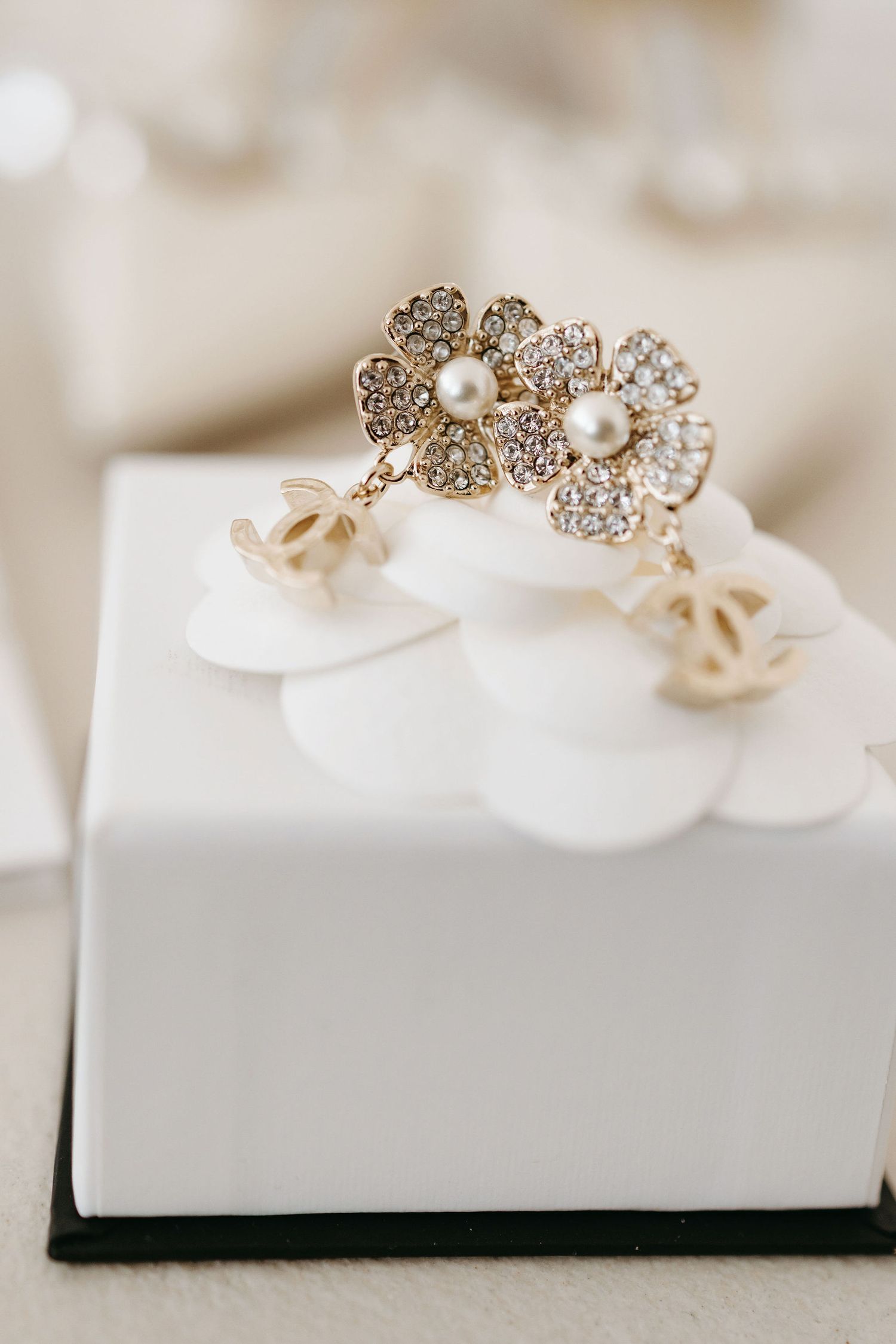 Delicate floral pearl and crystal stud earrings displayed on a white jewelry box.