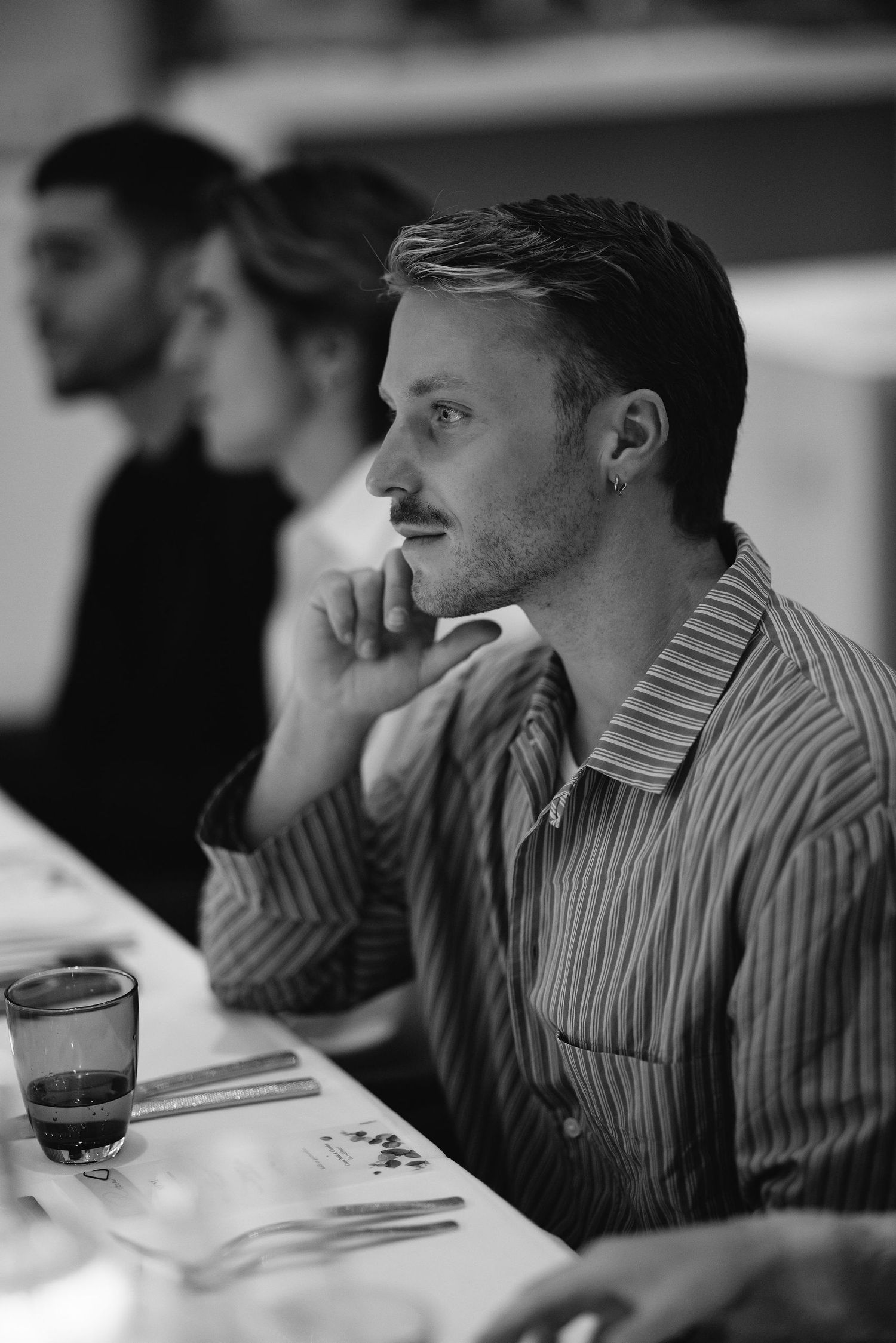 Black and white portrait of man in striped shirt sitting thoughtfully at table.