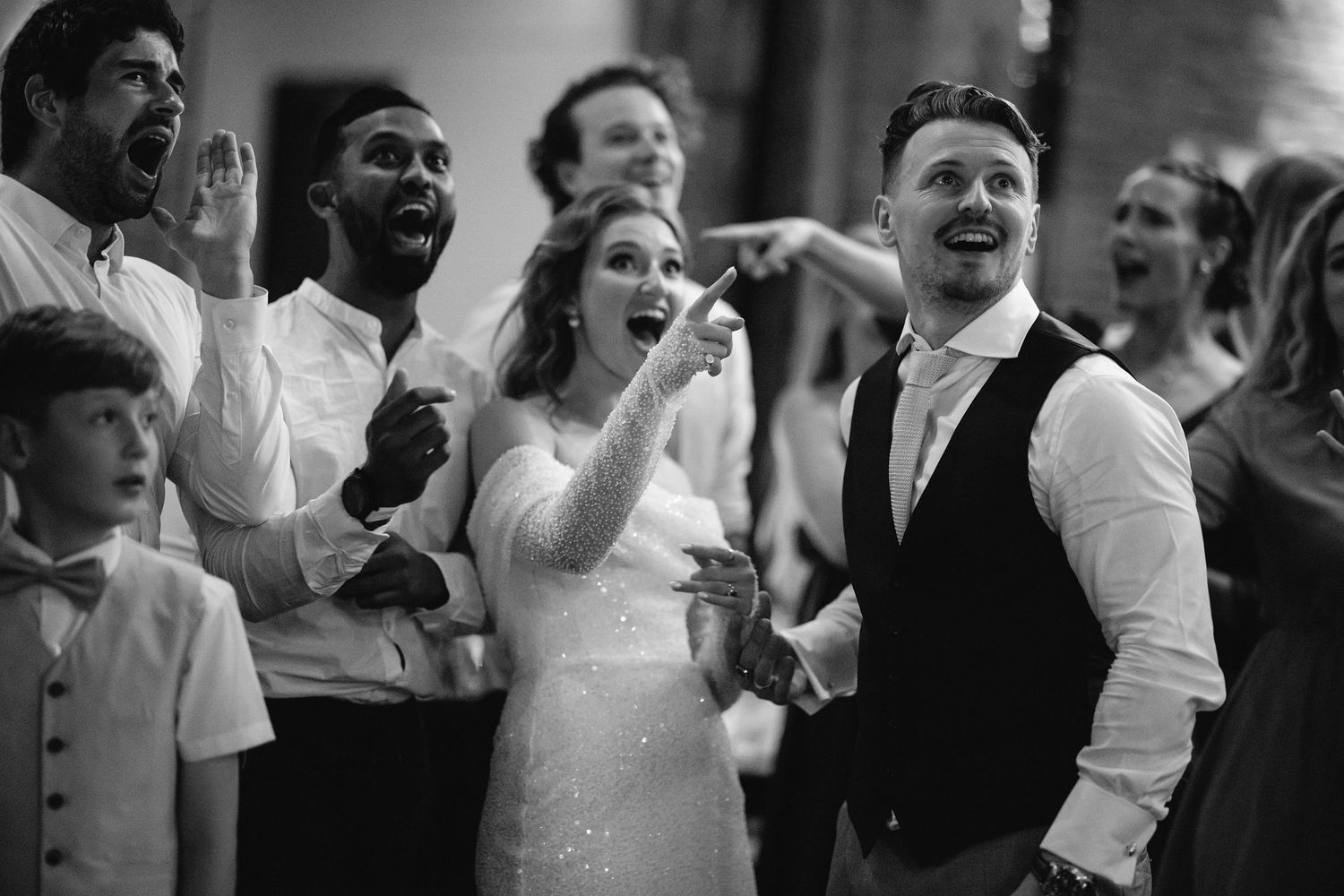 Wedding guests laughing and celebrating emotionally during a reception event.