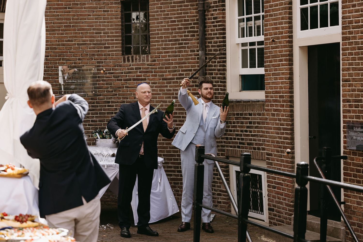 Wedding celebration outside a brick building with people enjoying festivities.