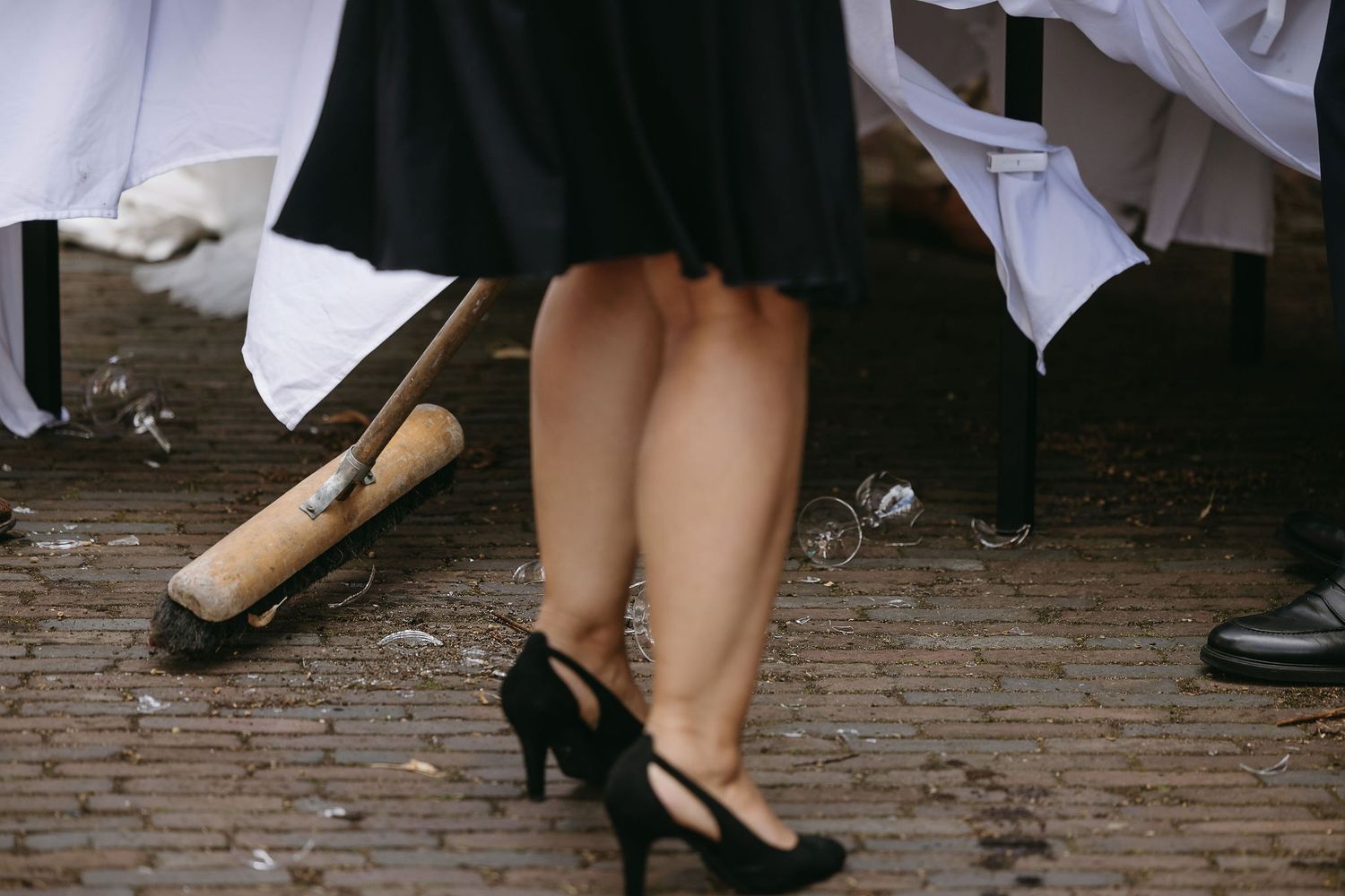 Dancing feet and shoes of wedding guests on cobblestone ground.