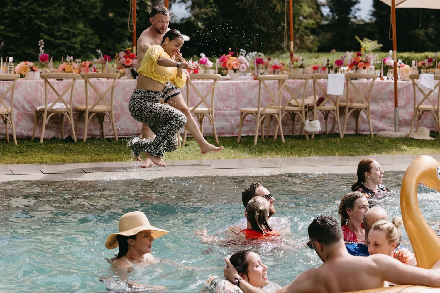 Wedding guests enjoying a pool party with inflatable floats and casual summer fun.