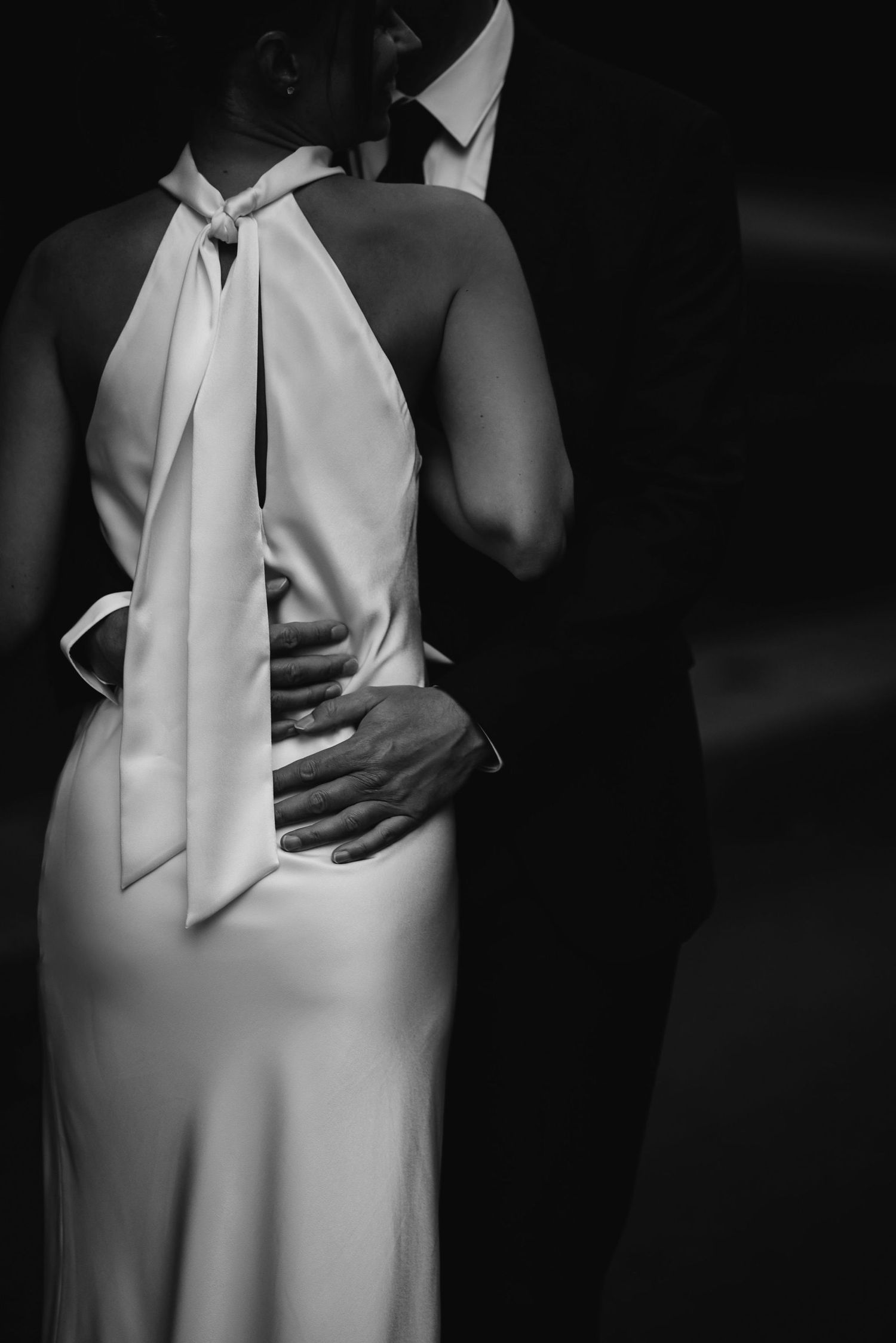 A dramatic black and white close-up of the back of a formal white dress with elegant draping.