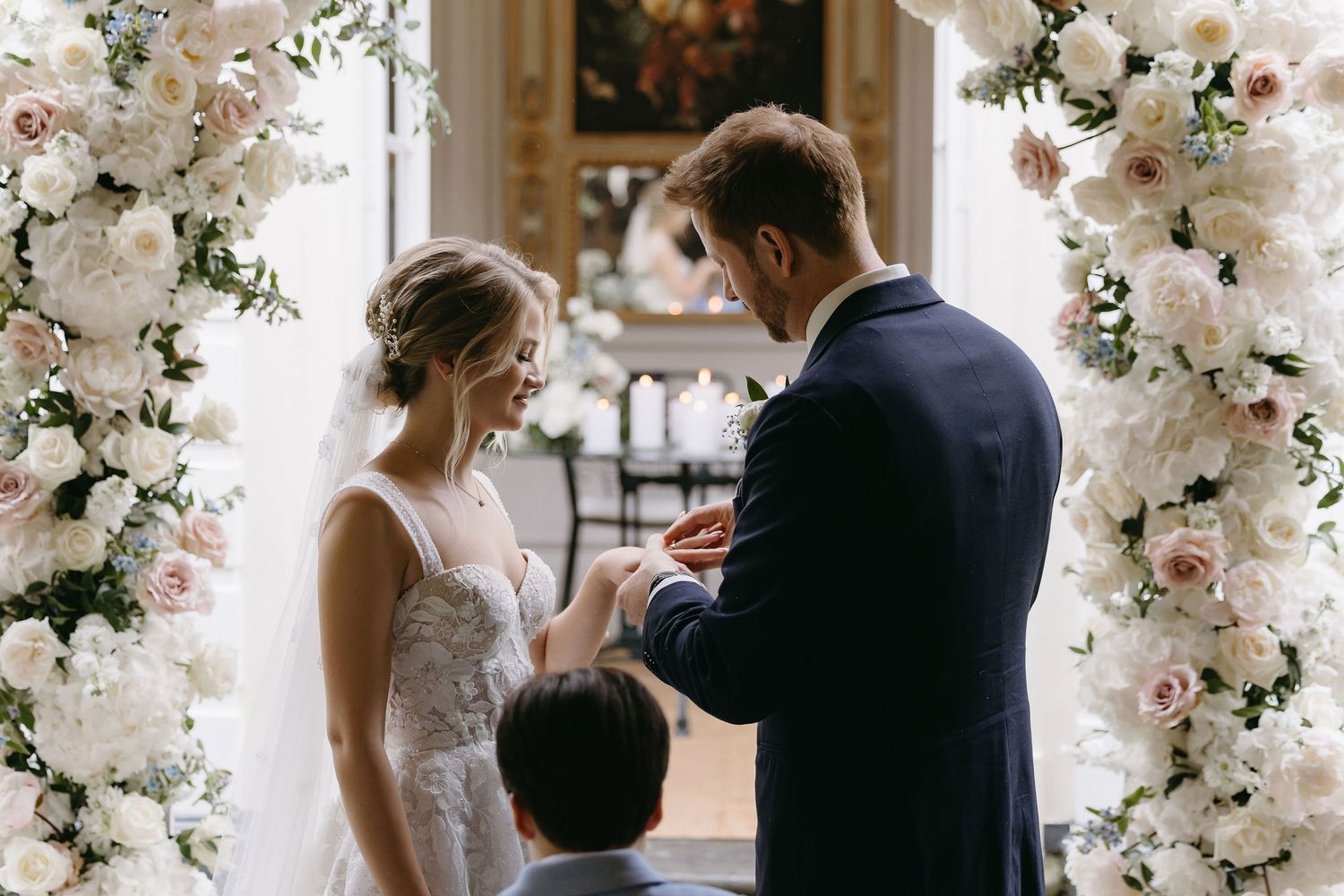 Wedding ceremony setup with elegant white floral arch arrangements and decorative elements.