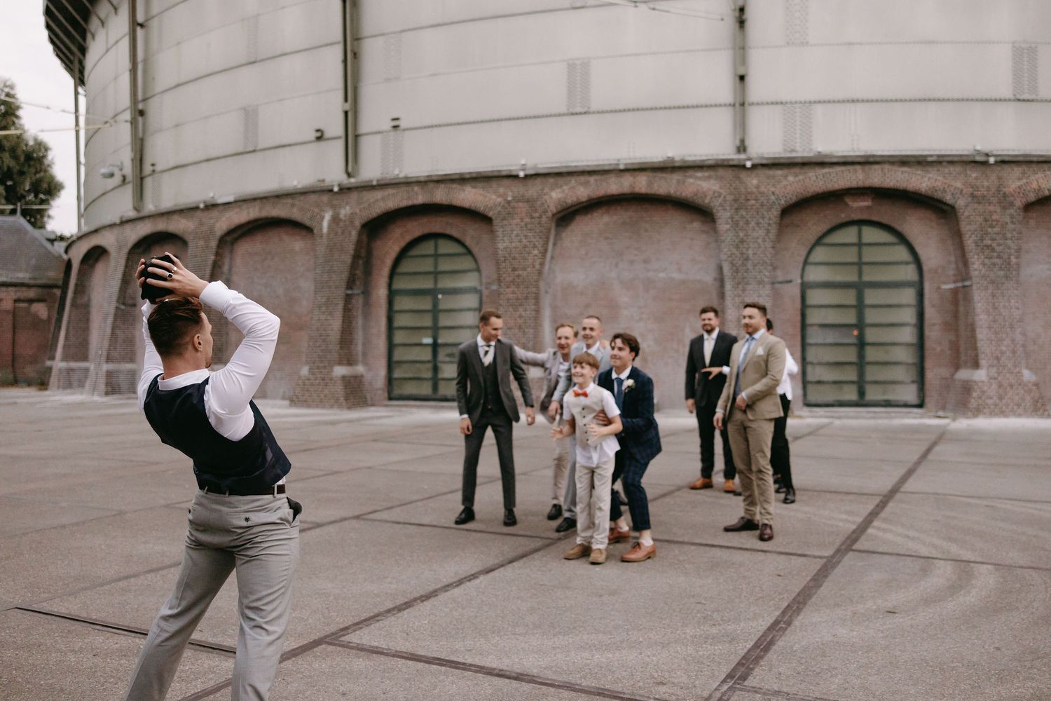 Wedding party playing interactive games in a stone courtyard during daytime celebrations.