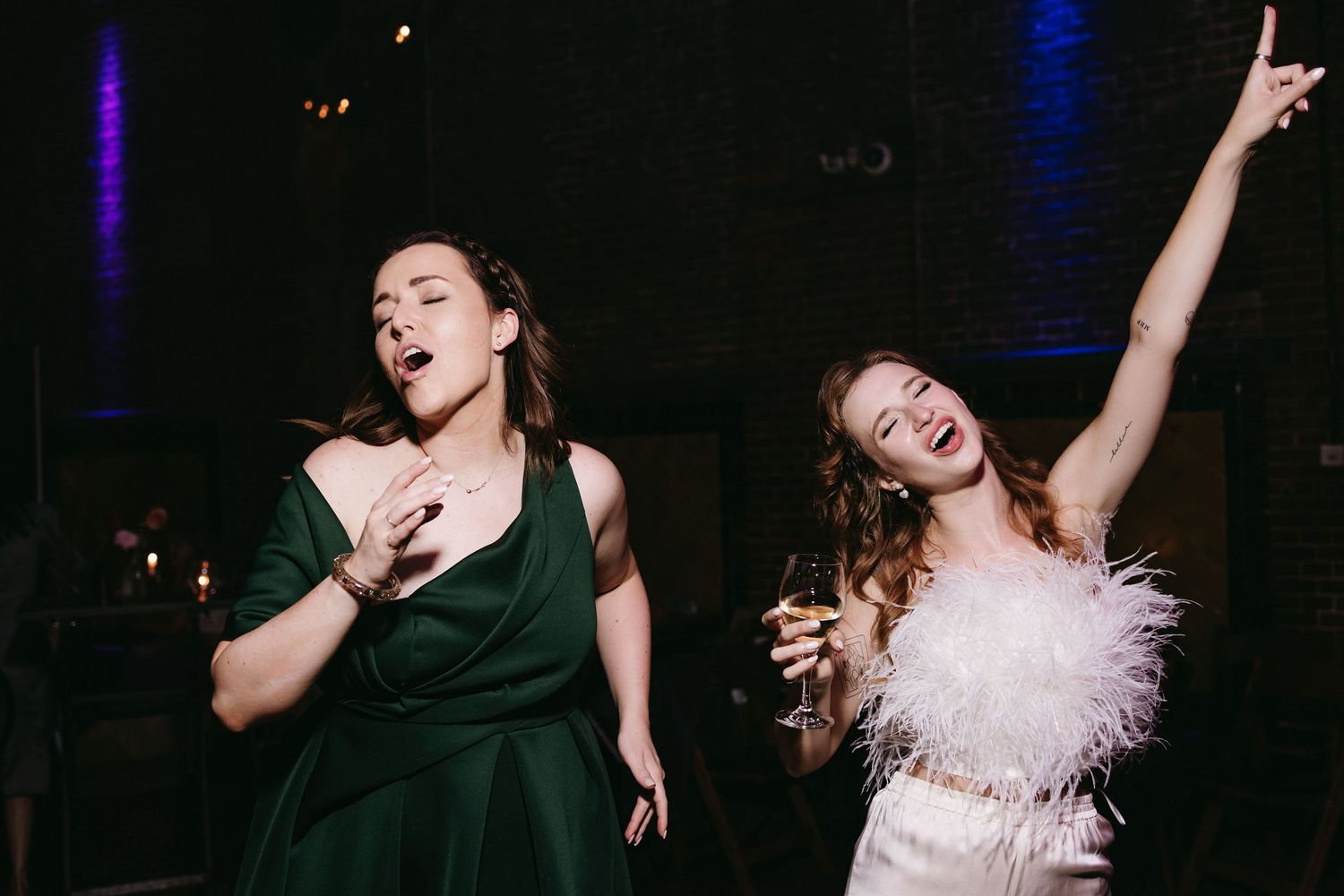 Wedding party dancing and celebrating under dramatic blue stage lighting.