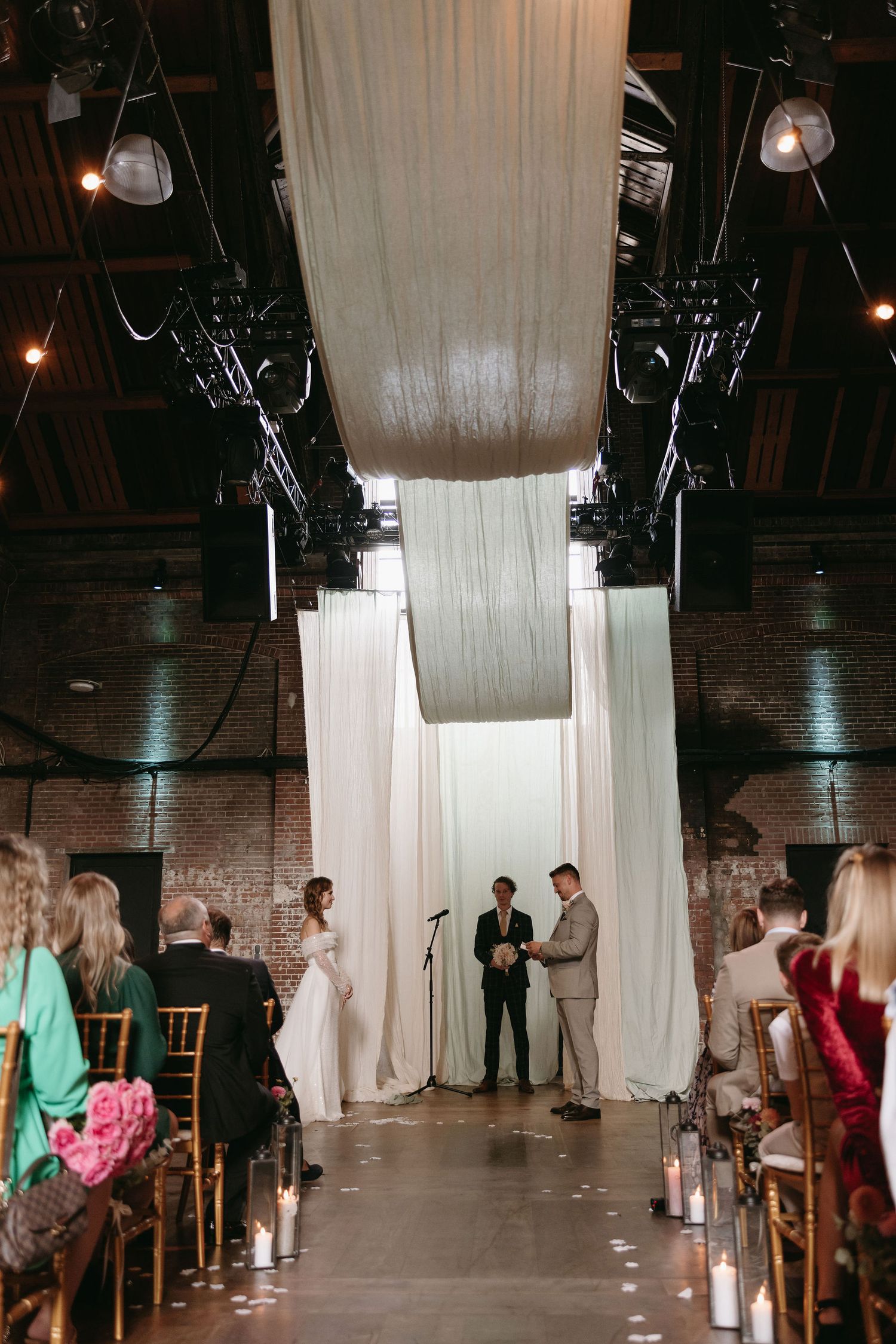 Wedding reception venue decorated with flowing white curtains and ambient lighting.