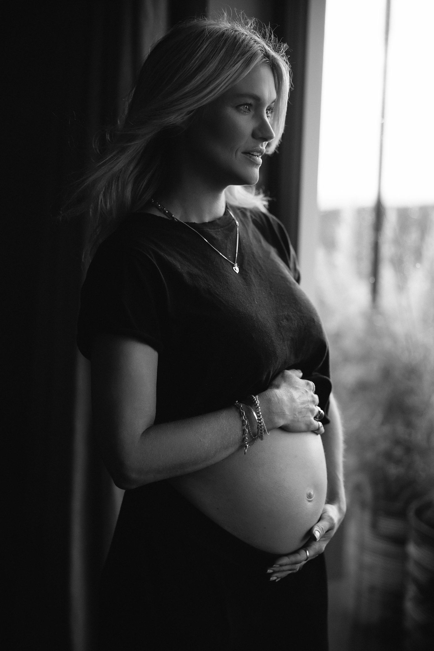 Intimate black and white maternity portraits near window with natural lighting.