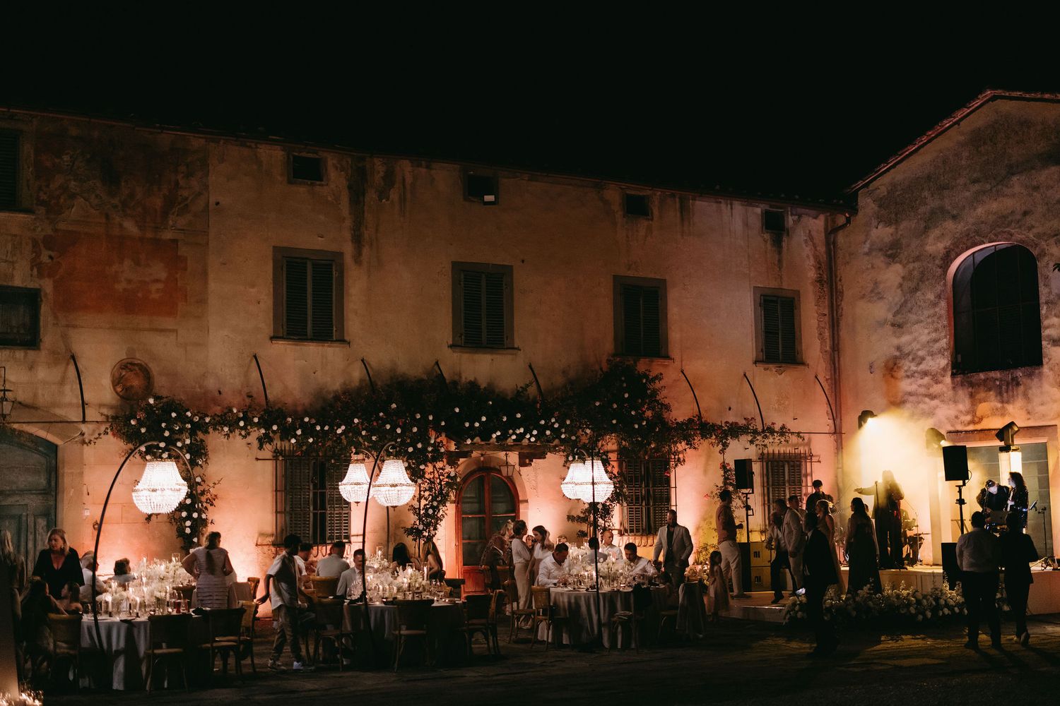 Historic villa facade illuminated at night with warm lighting and decorative string lights.
