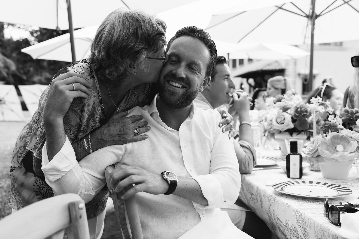 Black and white photo capturing a candid moment between guests at an outdoor reception.