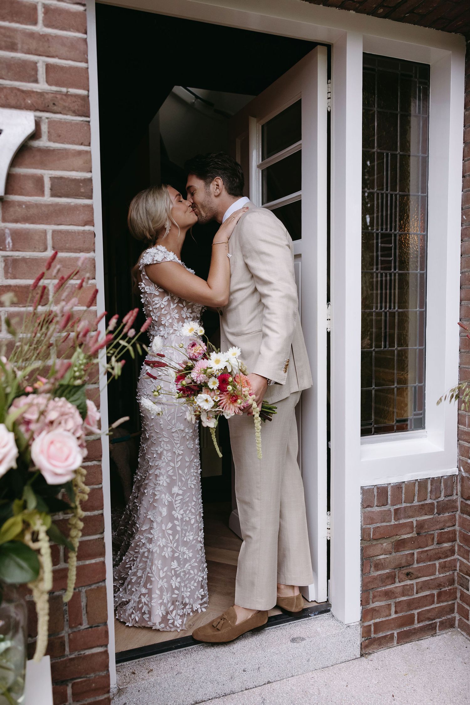Romantic wedding photo shoot by brick building with white windows.