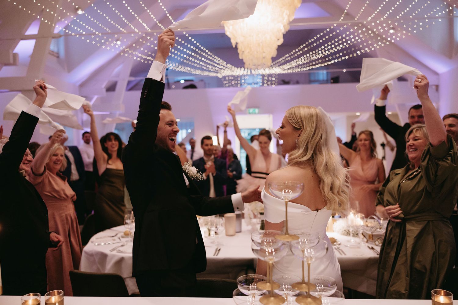 An elegant reception venue with hanging string lights creating a magical atmosphere for wedding celebrations.