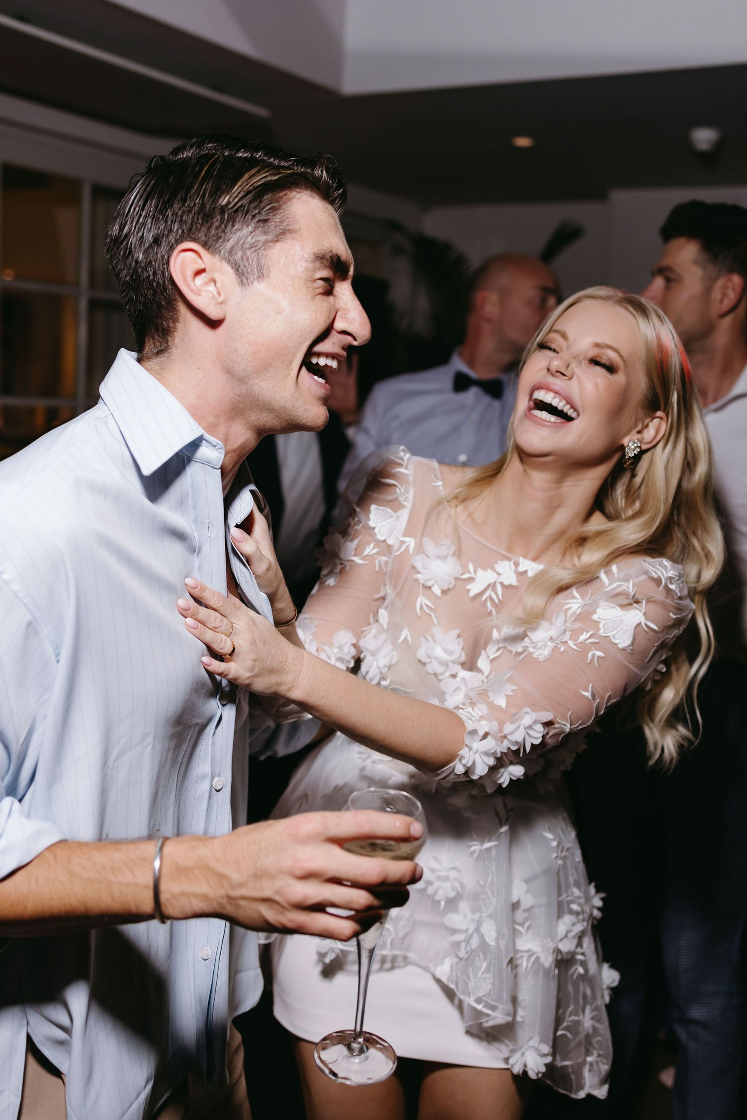 A couple shares a joyful moment laughing together at a wedding reception.