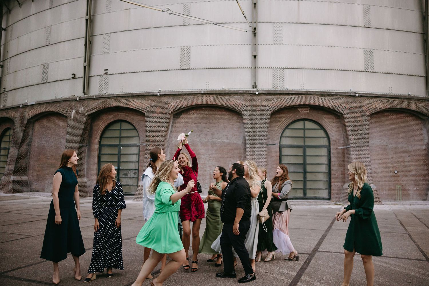 Wedding party posing together against stone architecture with curved arches.