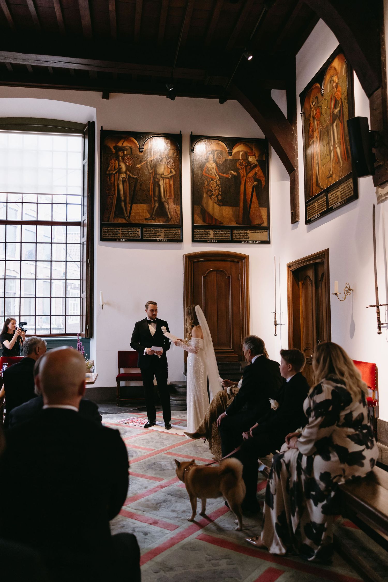 Interior view of a historic church with wooden panels and religious artwork during a ceremony.