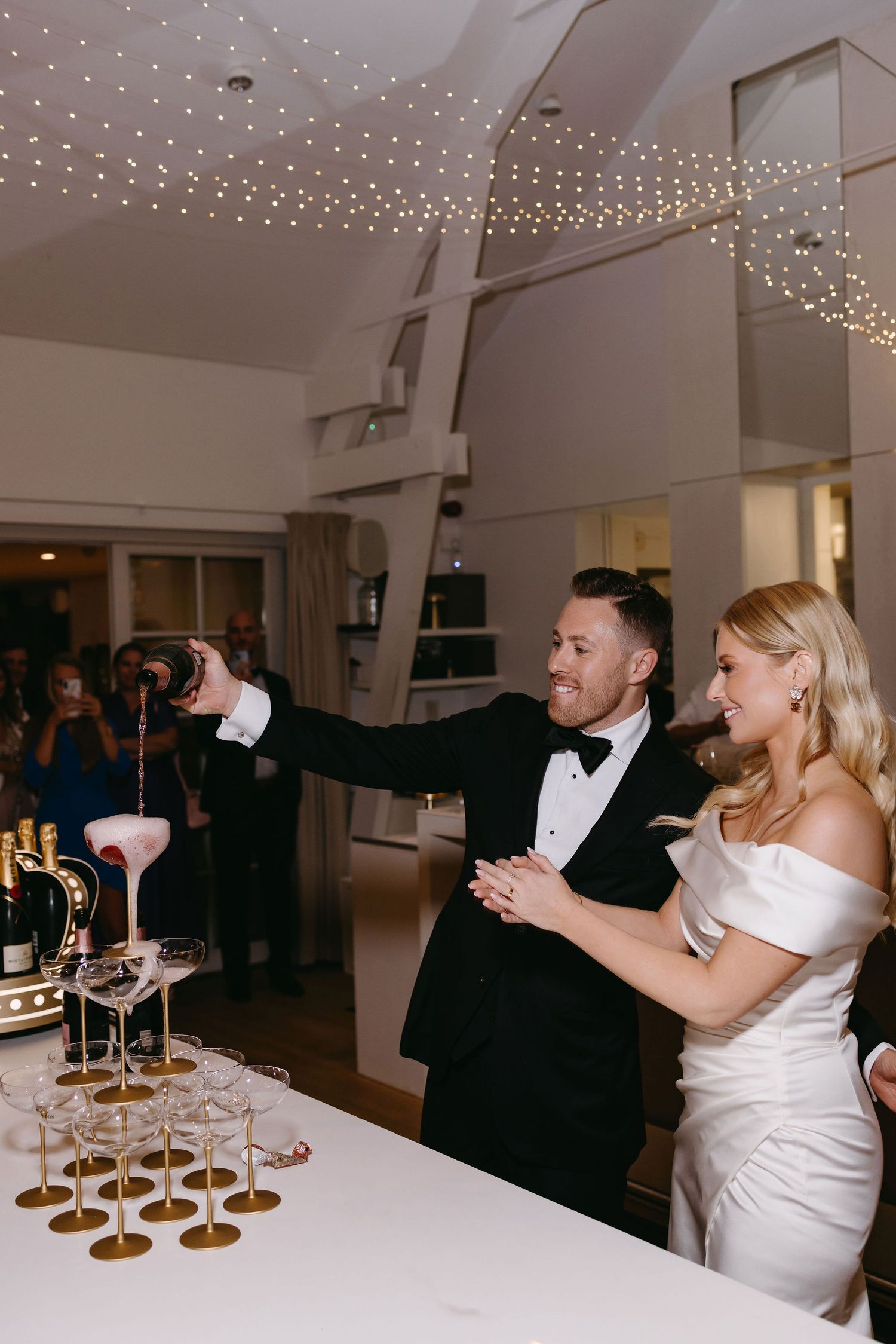 A sequence of images showing guests celebrating at an elegant wedding reception with champagne glasses and string lights.