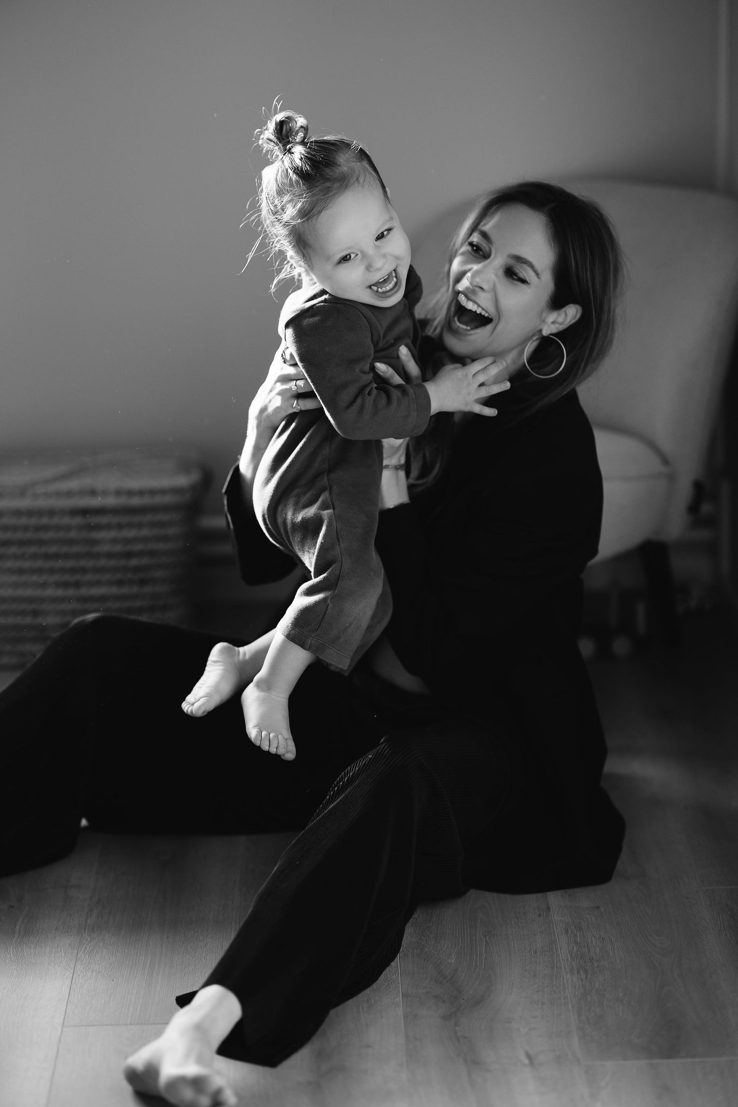 Joyful black and white candid moment of parent and child playing on floor.