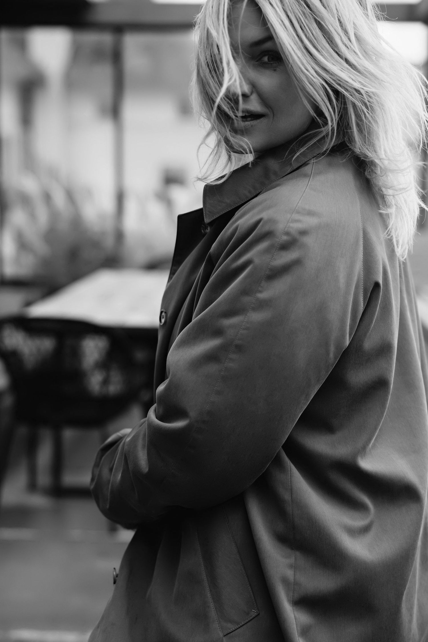 Black and white portrait of someone in an oversized coat with windswept hair.