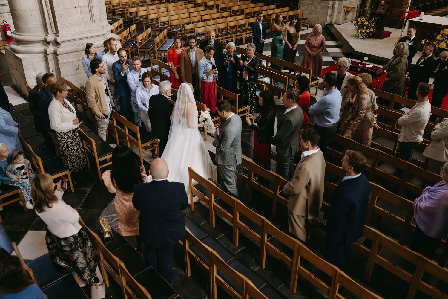 Overhead view of wedding ceremony taking place in traditional church with wooden pews.
