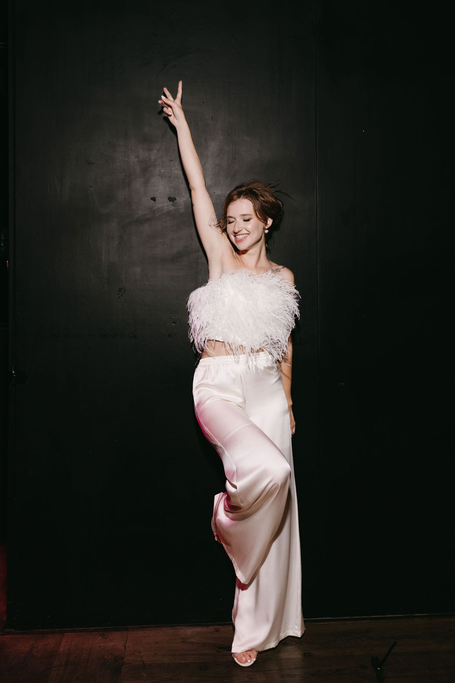 Joyful dancing poses in a flowing white dress against a dark dramatic background.