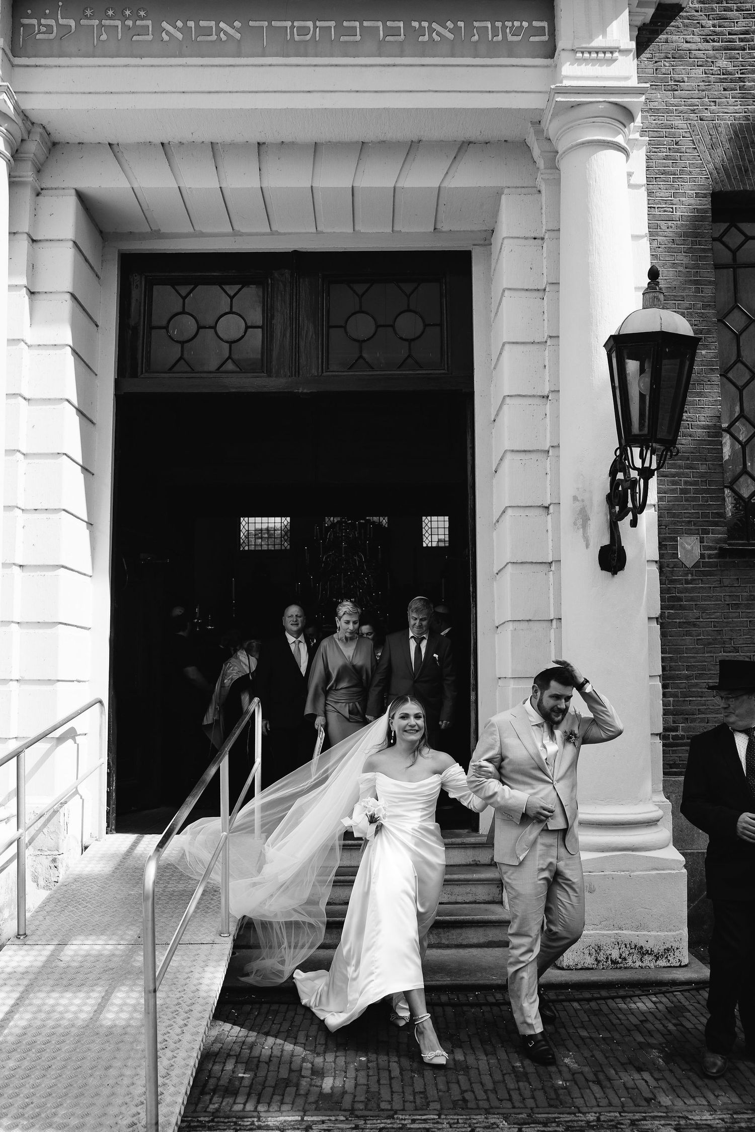 Sequence showing couple exiting through white columned entrance in playful poses.