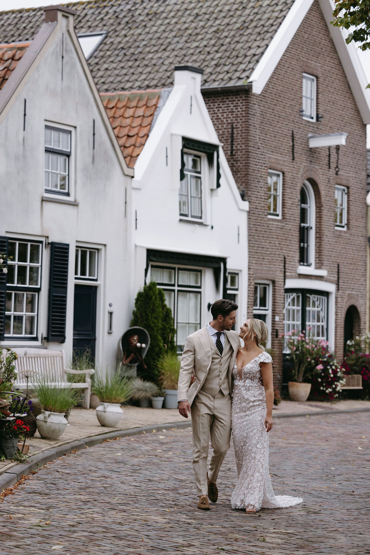 Couple walking hand in hand through charming European street with traditional architecture.