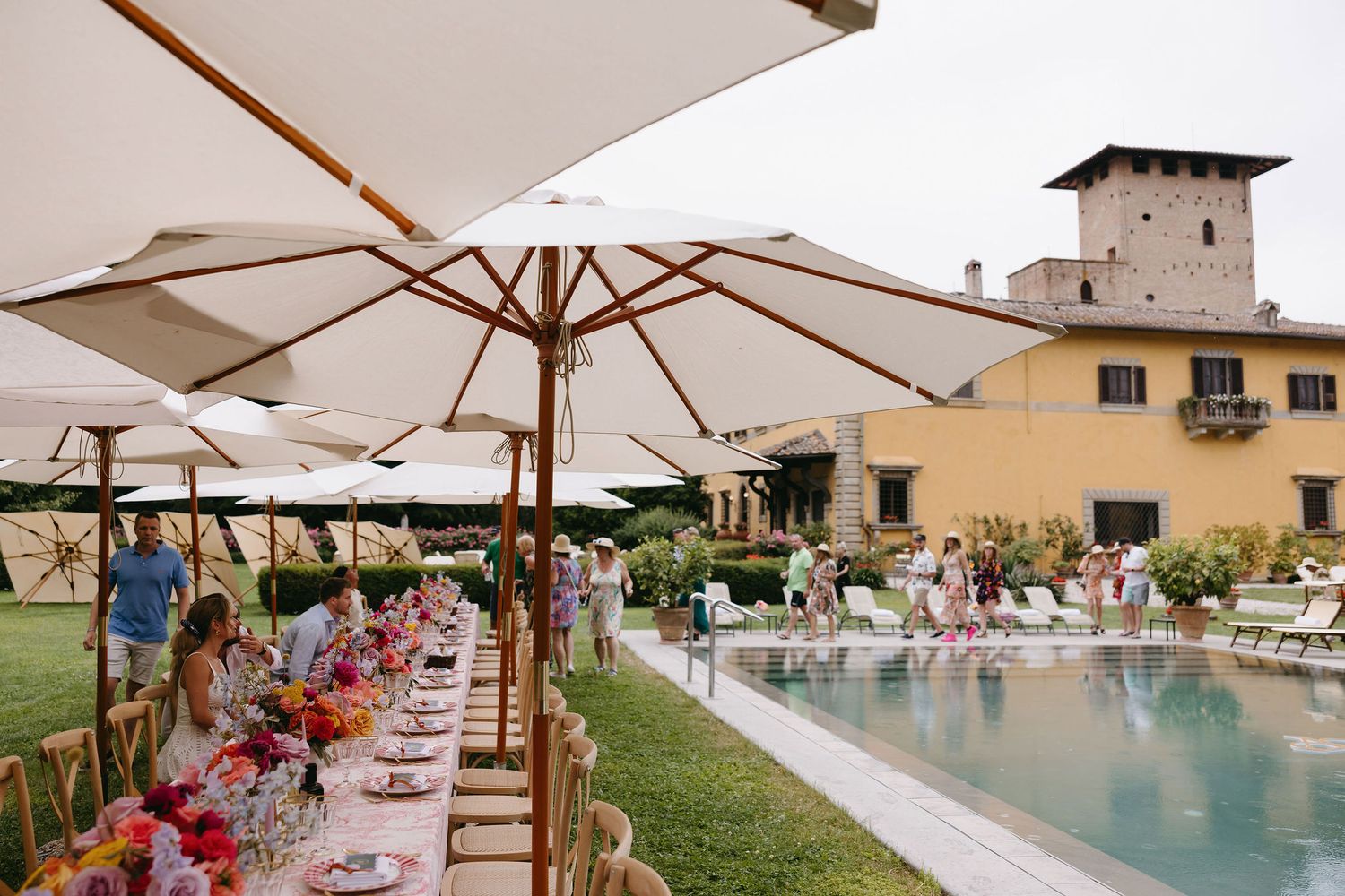 Outdoor venue with white umbrellas and swimming pool for a destination wedding.