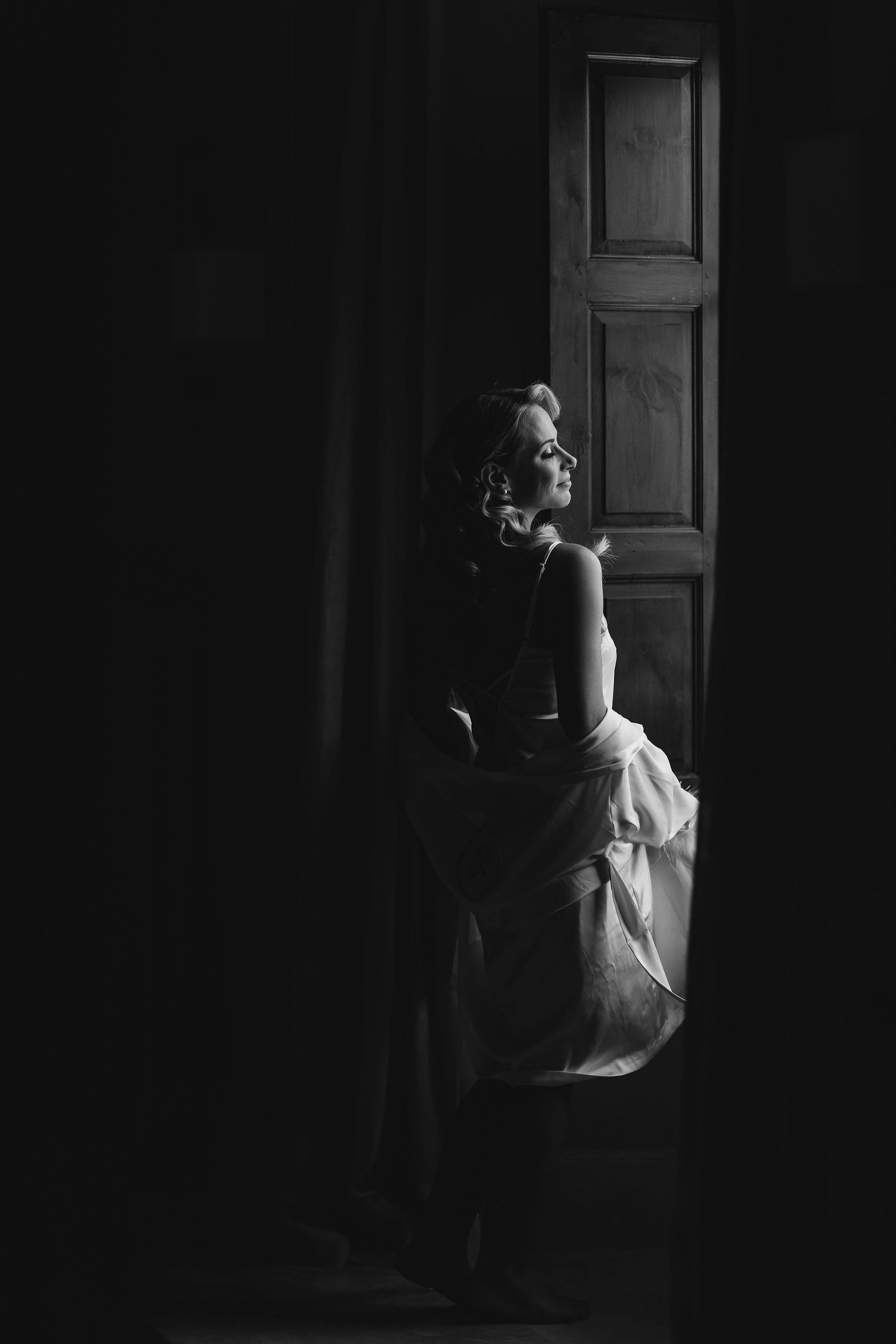 A dramatic black and white photo showing a silhouette against light streaming through a wooden door.