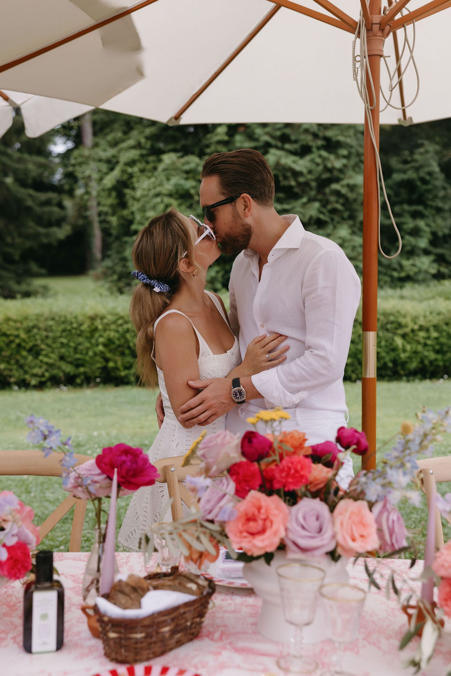 Romantic scene under a white umbrella with flowers and picnic setup.