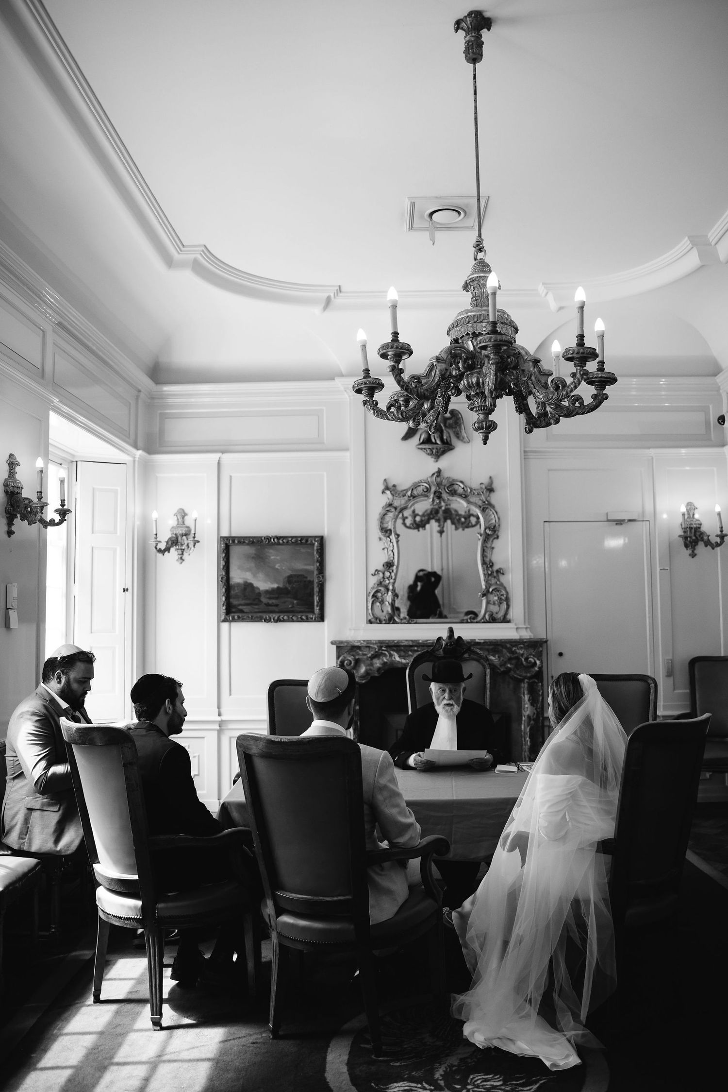Elegant room with chandeliers and luxurious furnishings during wedding ceremony.